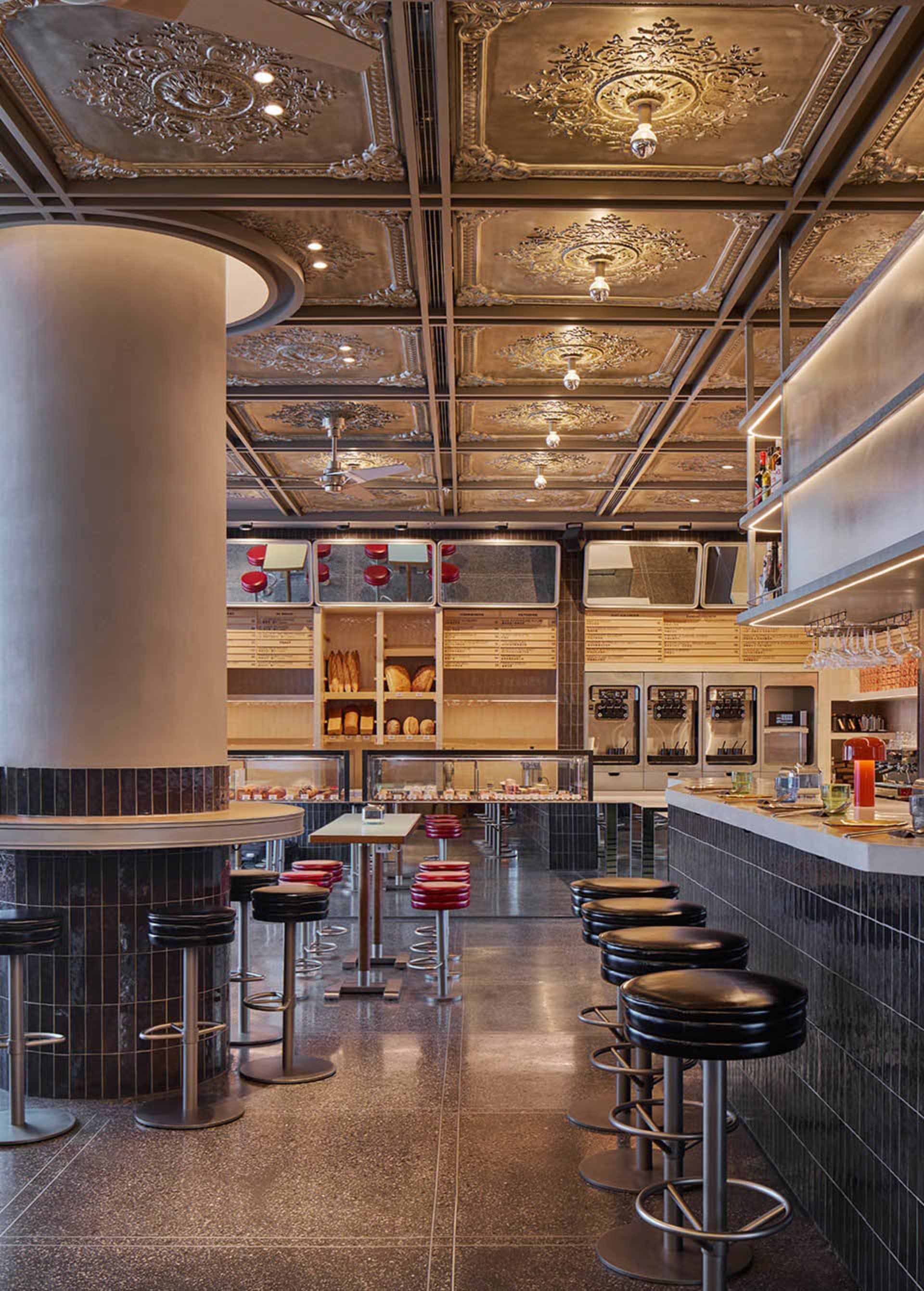 A modern industrial restaurant featuring metallic accents, wooden furniture, and tiled flooring.