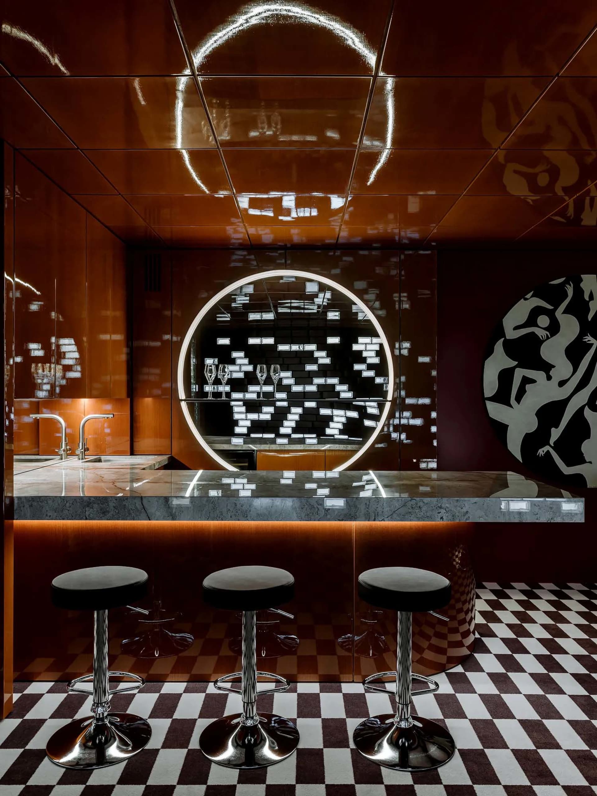 Modern bar counter featuring black and white tiles, metallic ceiling, and stools.