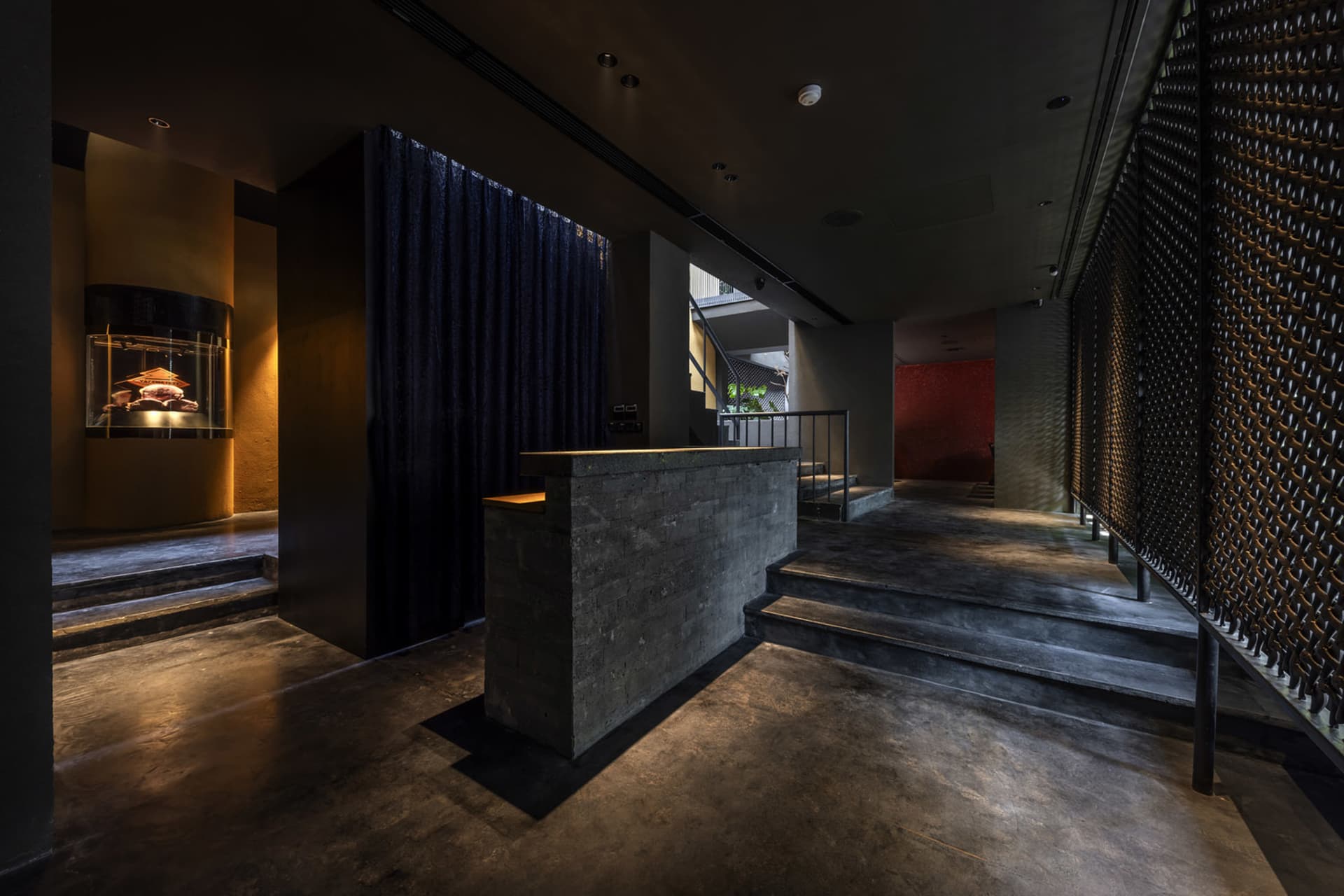 A sleek, modern hotel lobby featuring concrete, glass, and metal materials.