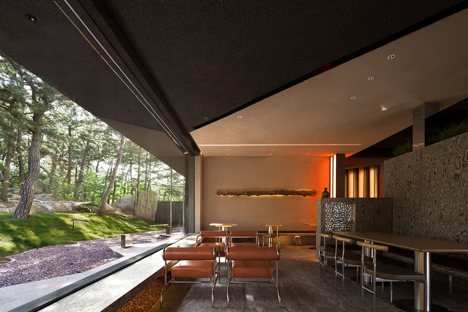 A modern restaurant interior with concrete walls and natural wood accents.