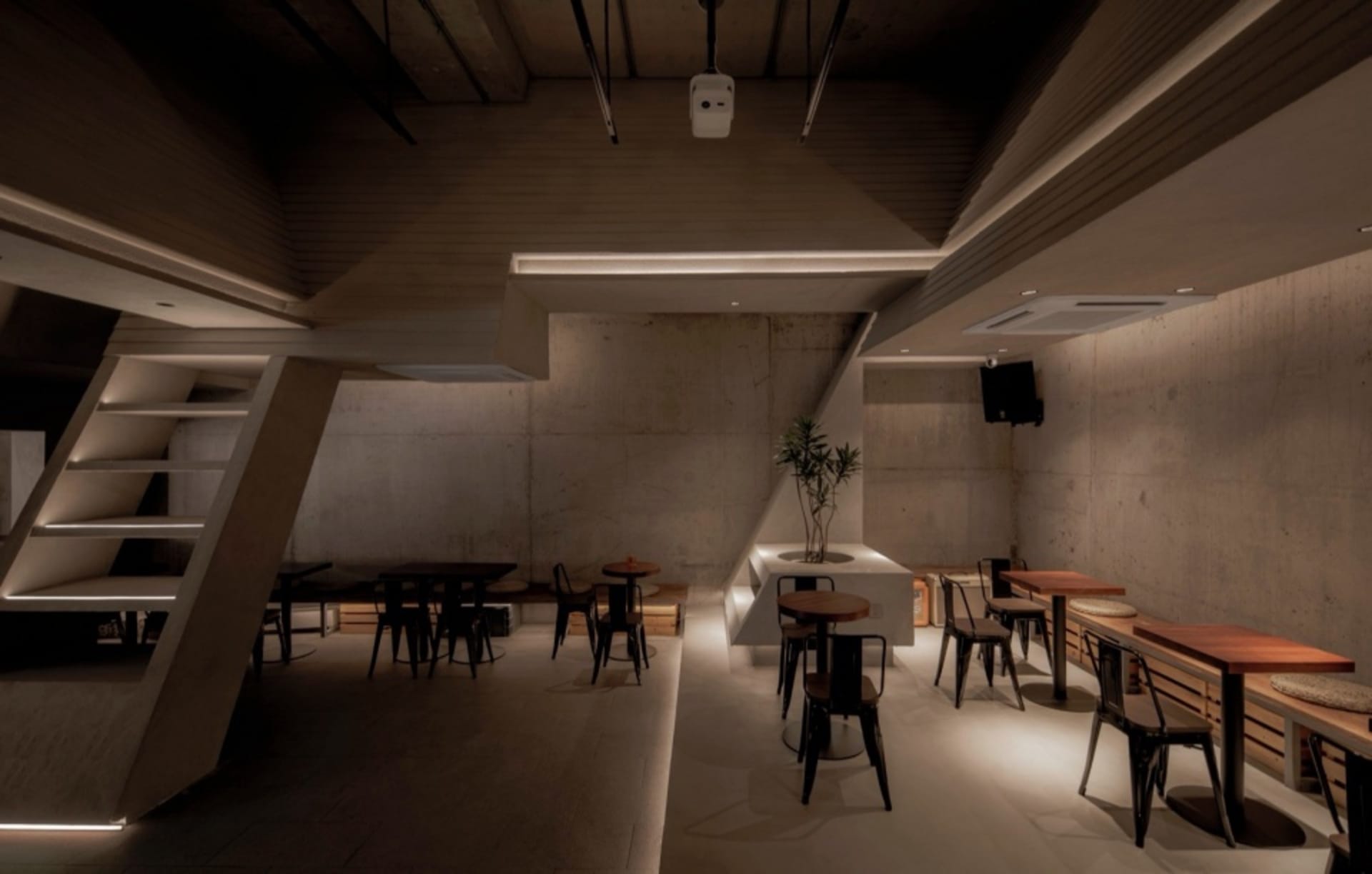 一間現代工業風餐廳，擁有混凝土牆面、木製餐桌與金屬椅。