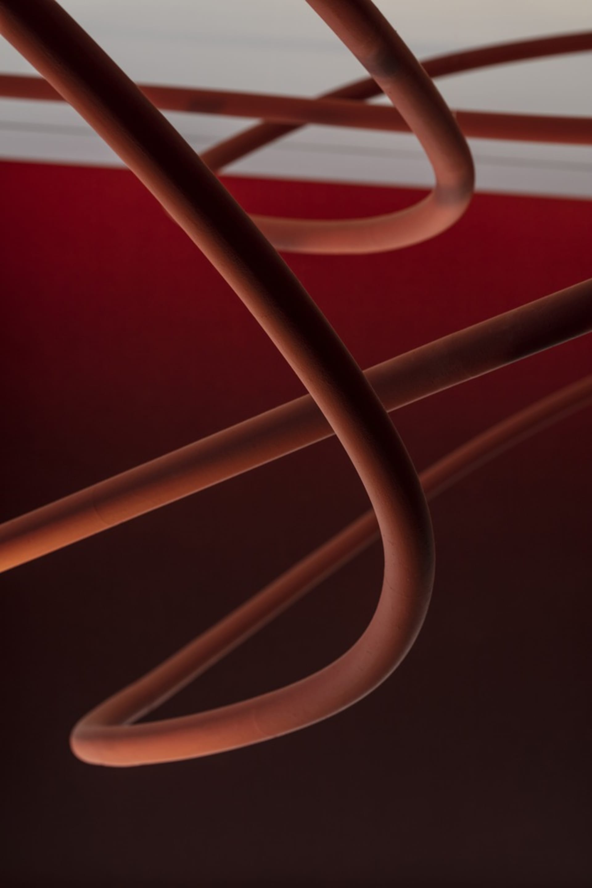 Red copper pipes arranged in a minimalist pattern against a dark background.