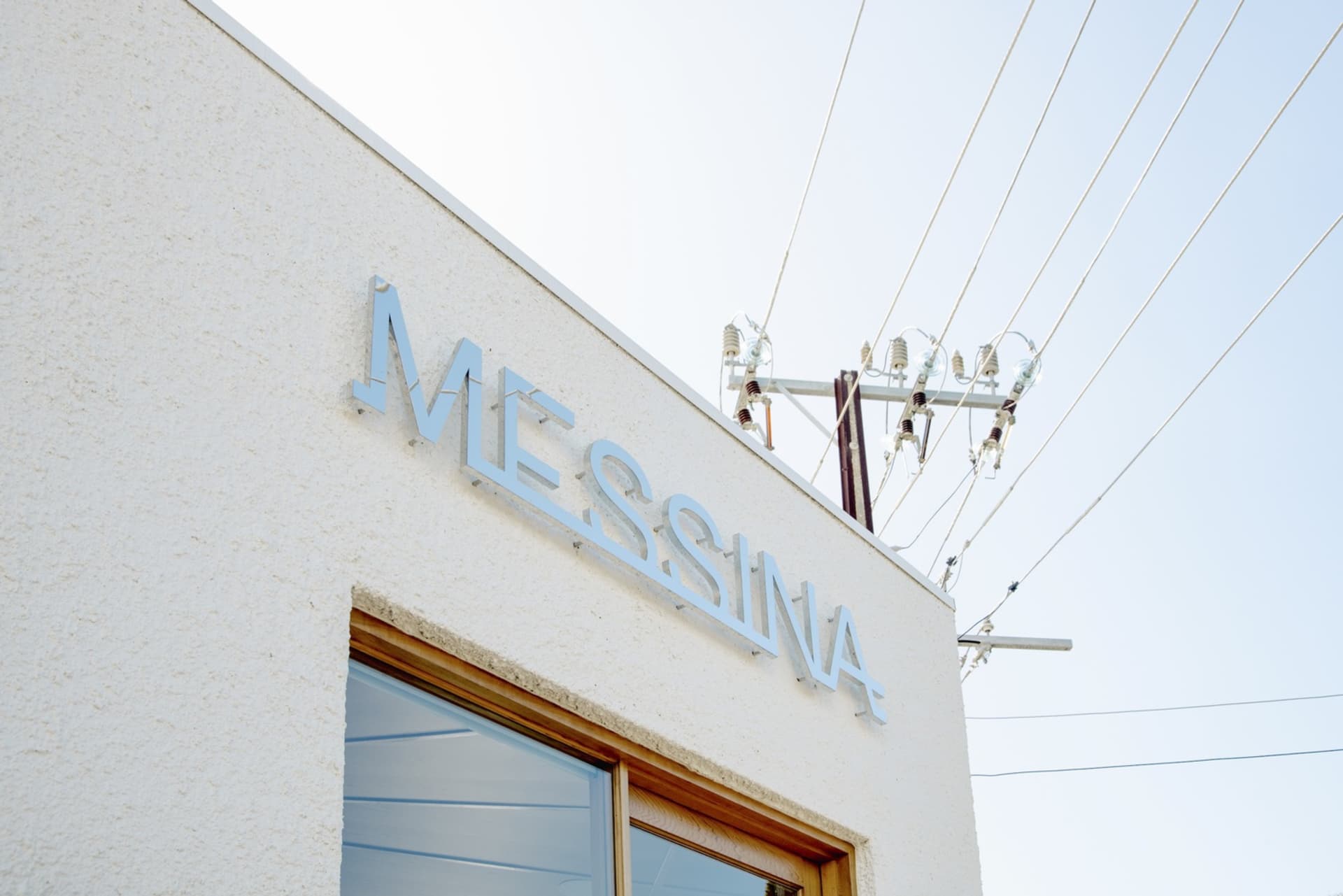 The Messina building exterior features clean white walls with blue signage reading "Messina"