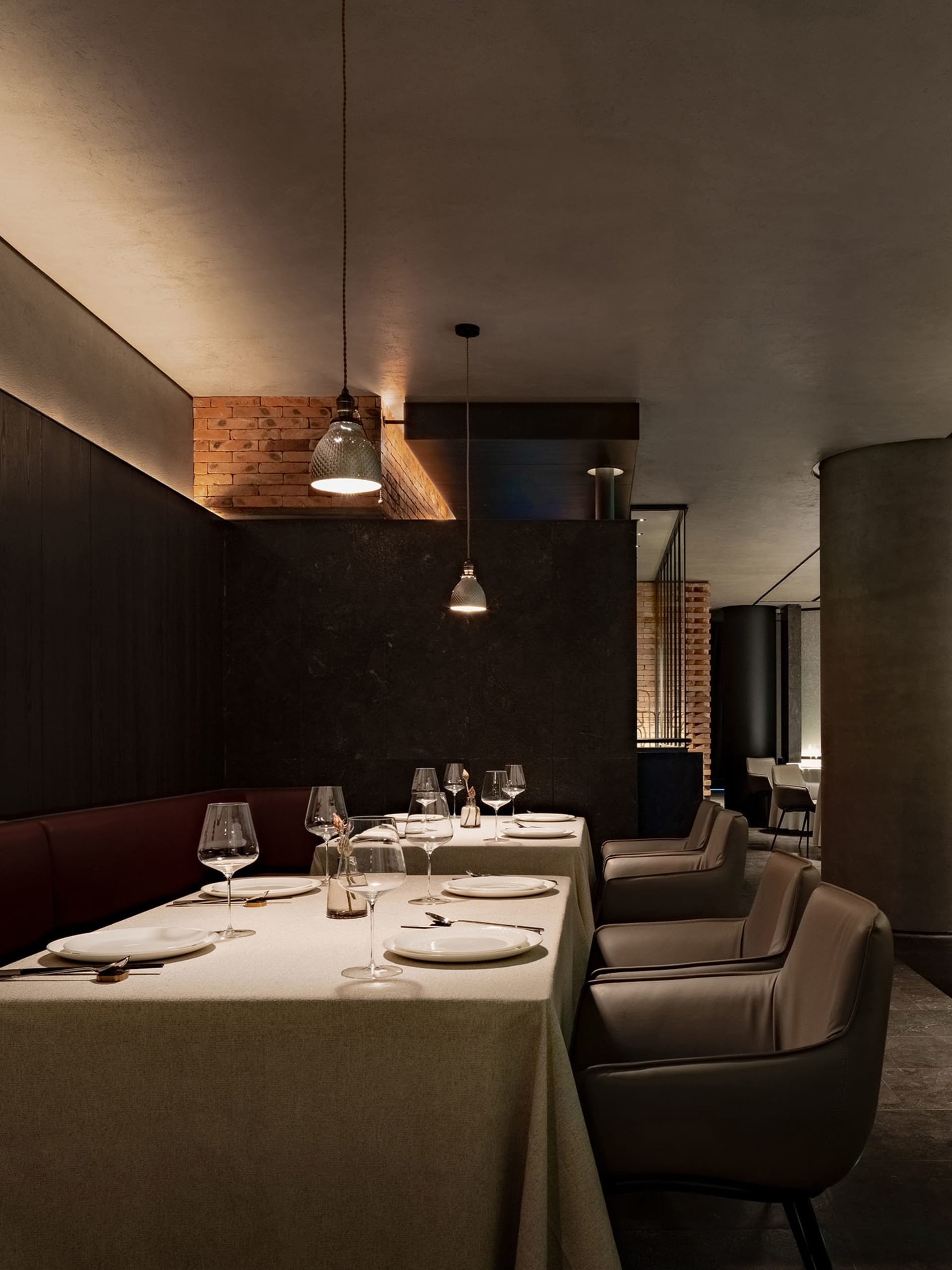 A modern restaurant interior showcasing sleek, concrete finishes with minimalistic design and warm lighting.