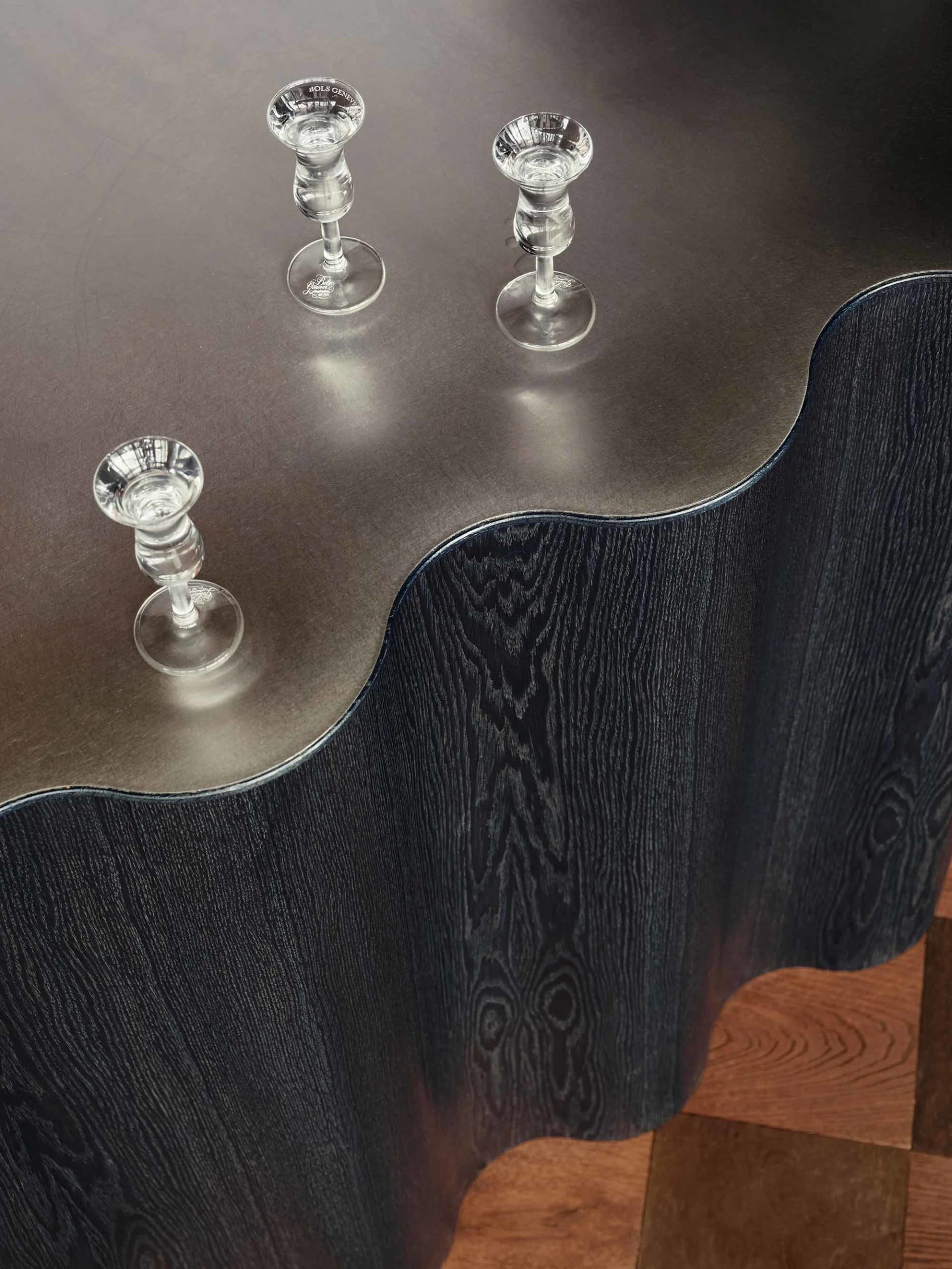A sleek, minimalist metal table with a smooth, wave-shaped surface.