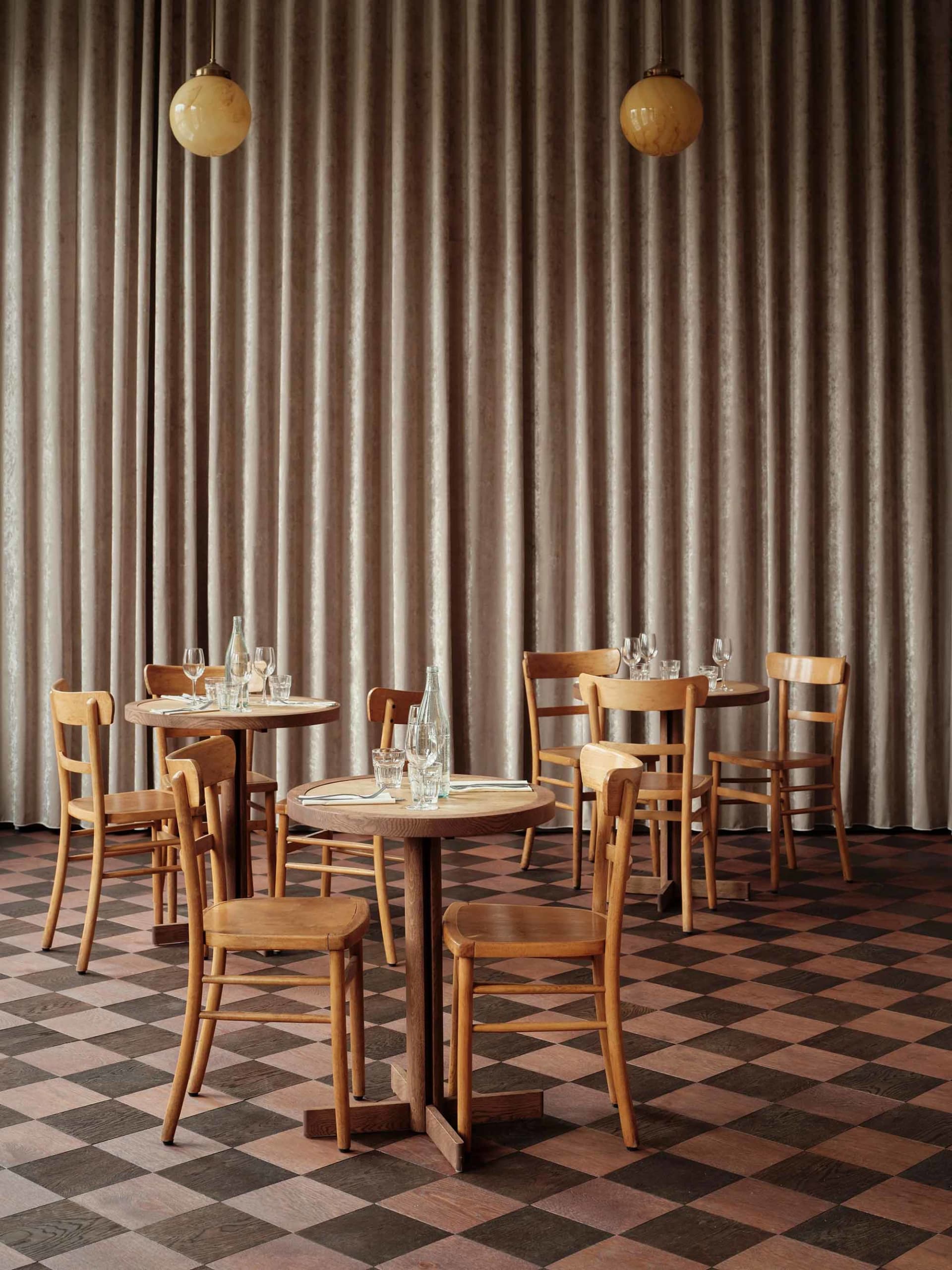 Modern restaurant interior with wooden furniture and checkered floor.