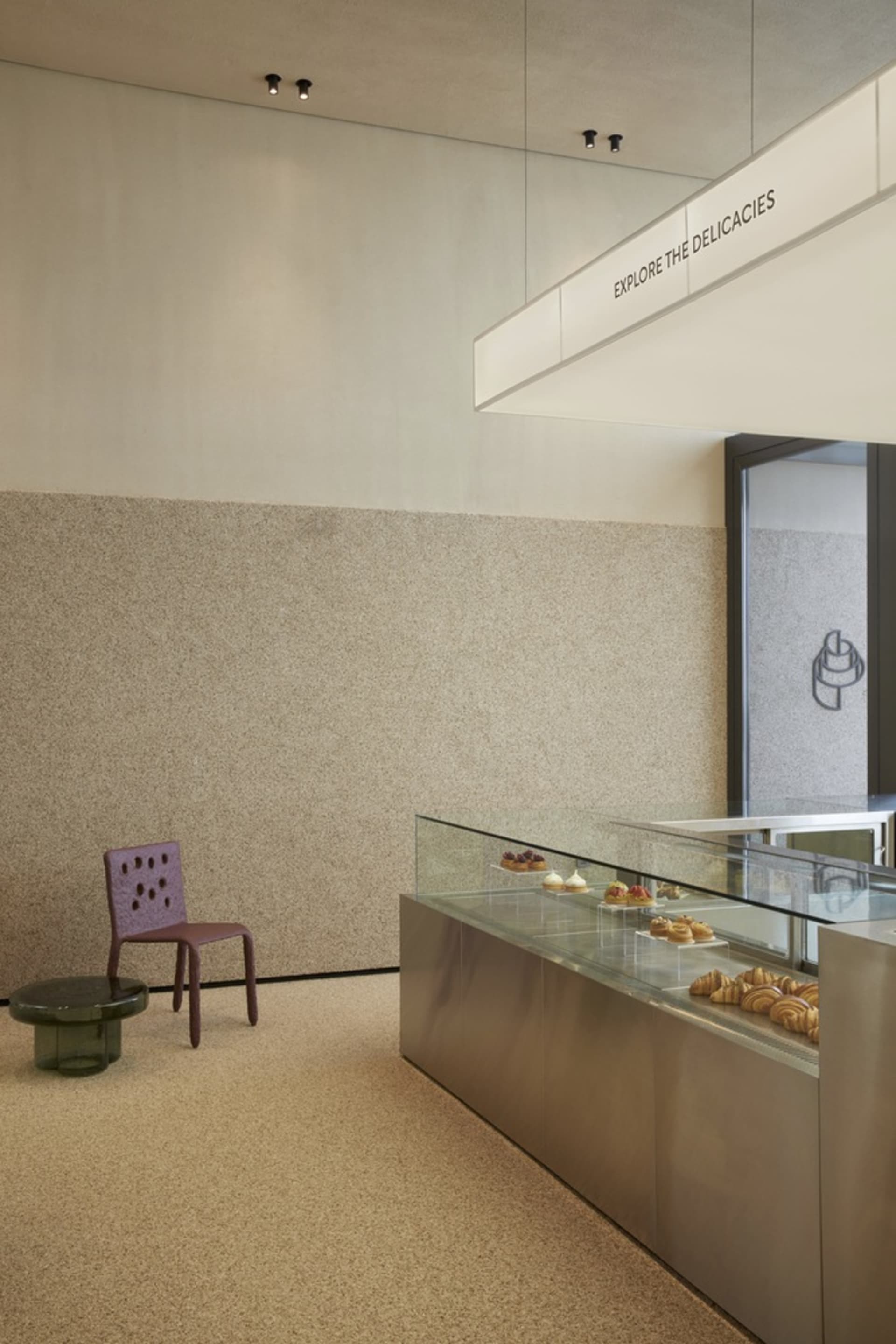 Modern bakery interior with a glass display case filled with pastries and a marble countertop.