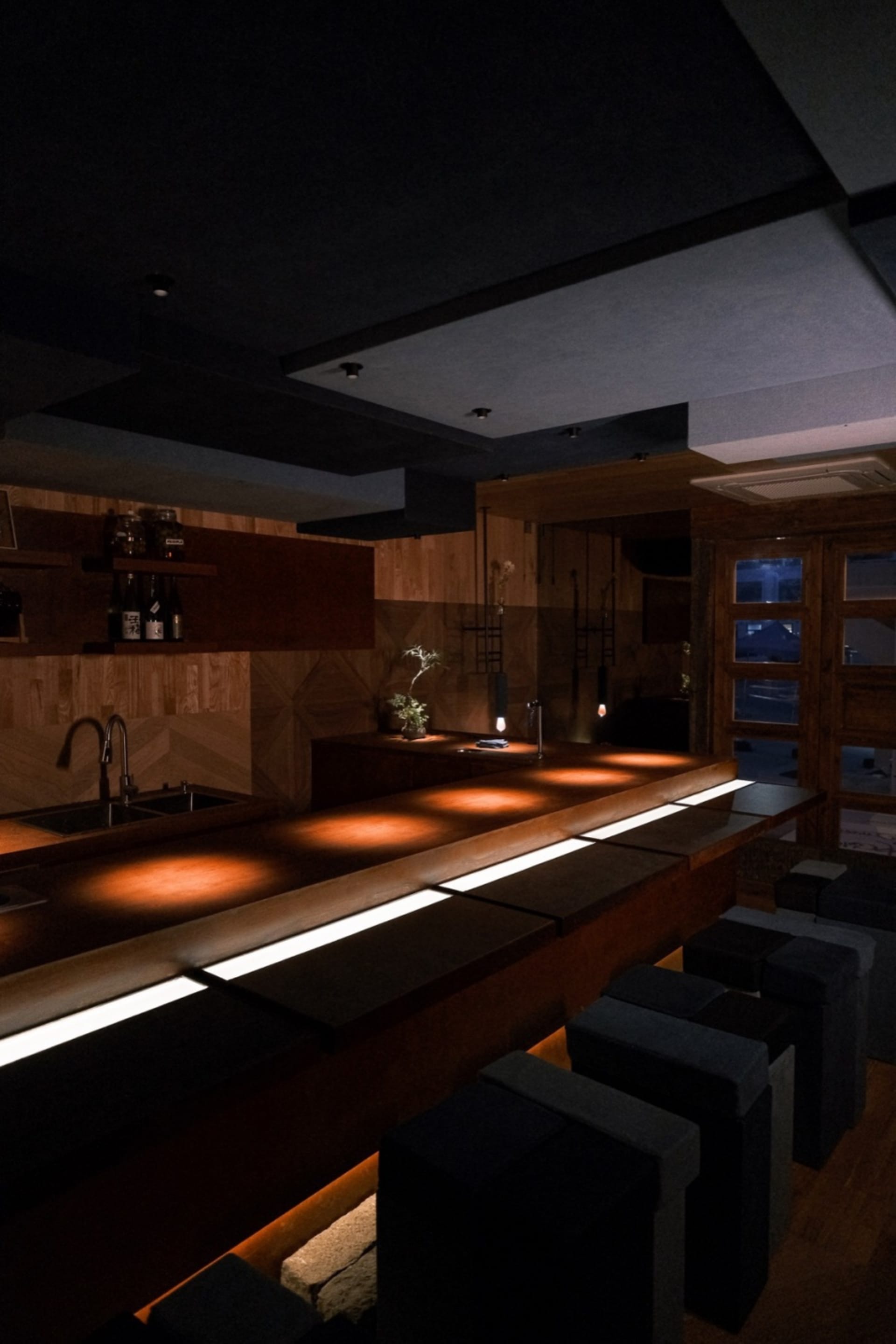 A modern restaurant bar with wooden interiors, neon lights, and comfortable seating