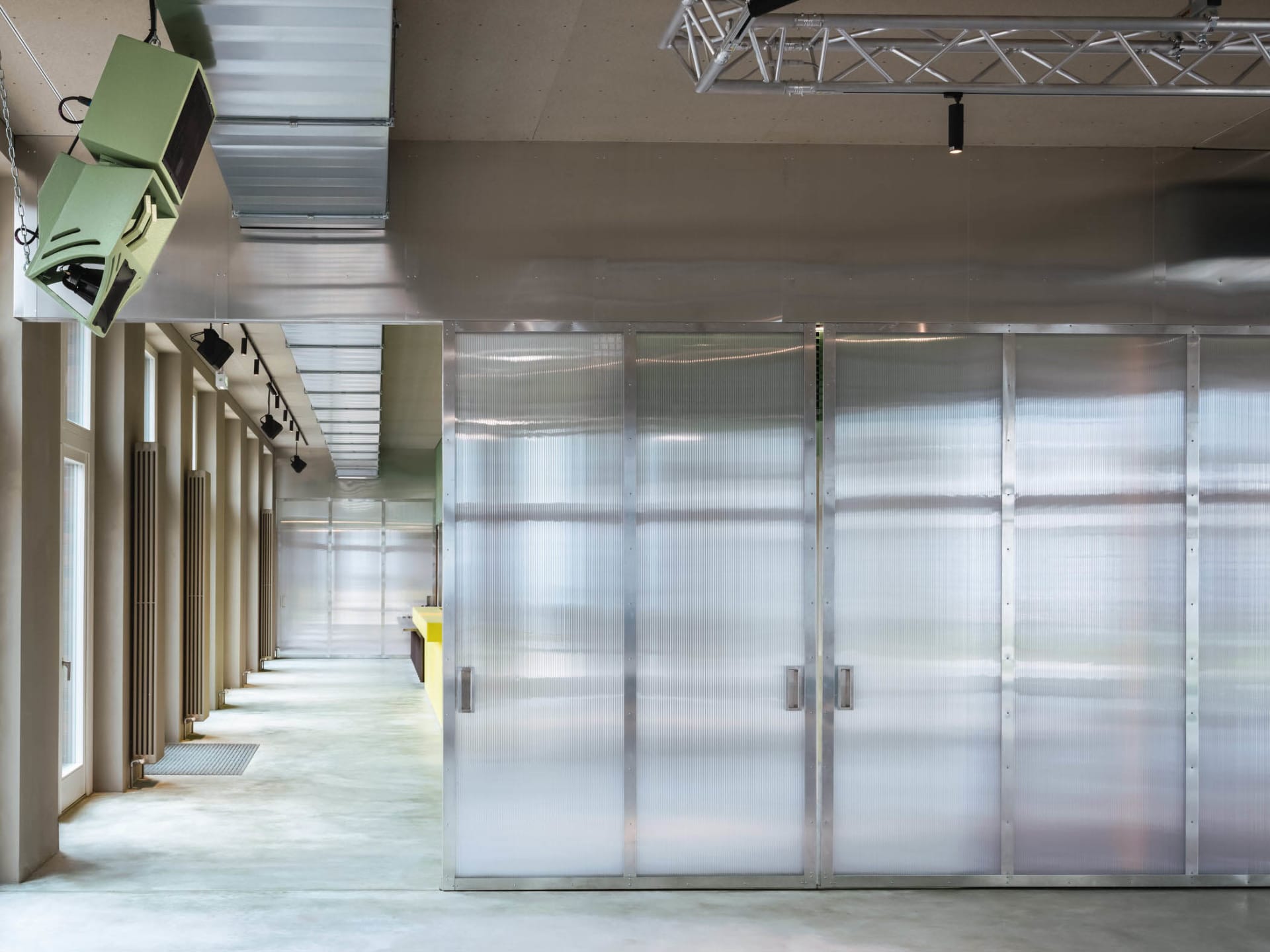 A minimalistic corridor with frosted glass partitions and metallic structures.