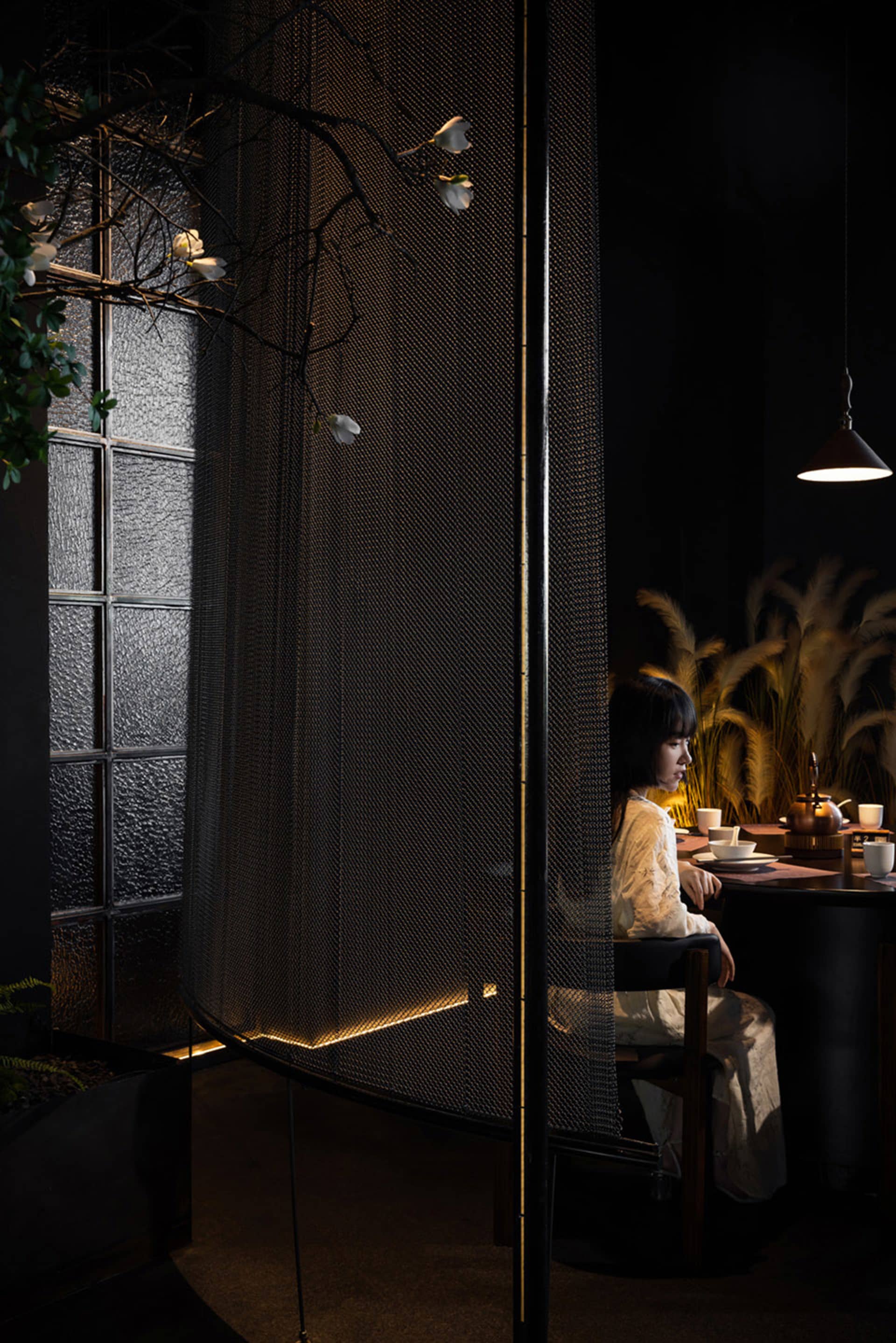 A sleek, modern restaurant booth constructed with metal netting and illuminated from below, featuring a minimalist interior d
