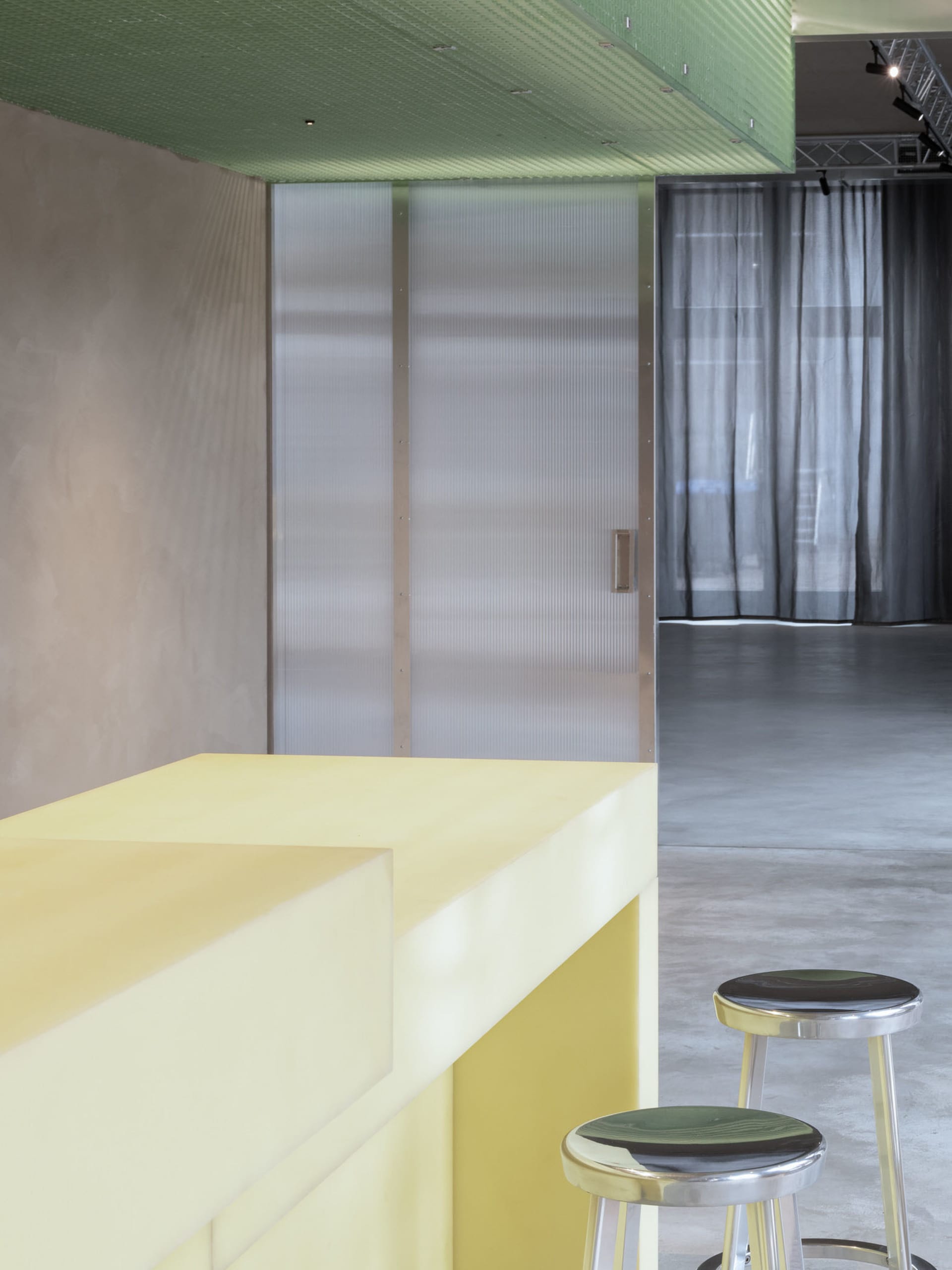 A modern bar area with a yellow countertop and concrete floor.