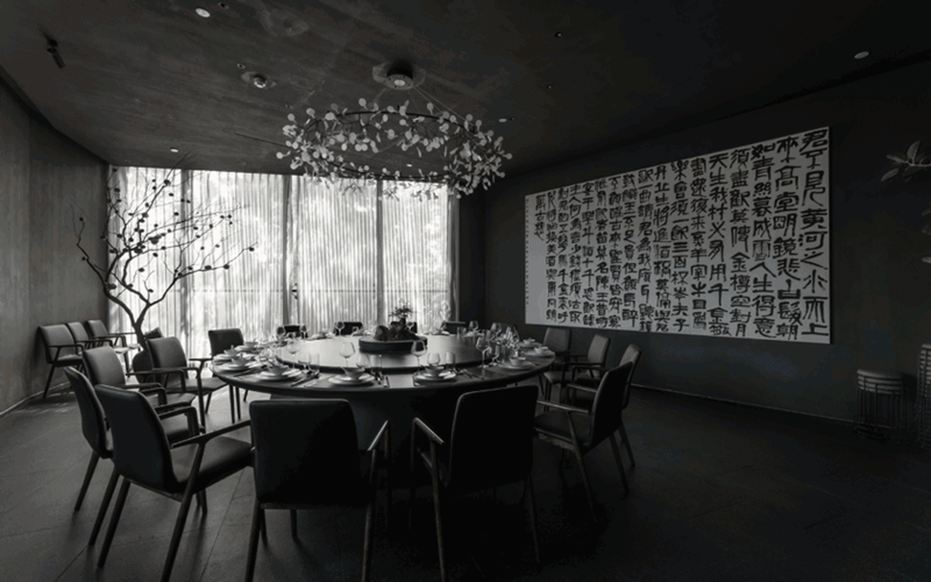 A modern, industrial-style restaurant interior featuring a circular dining table surrounded by black chairs, with a black-and