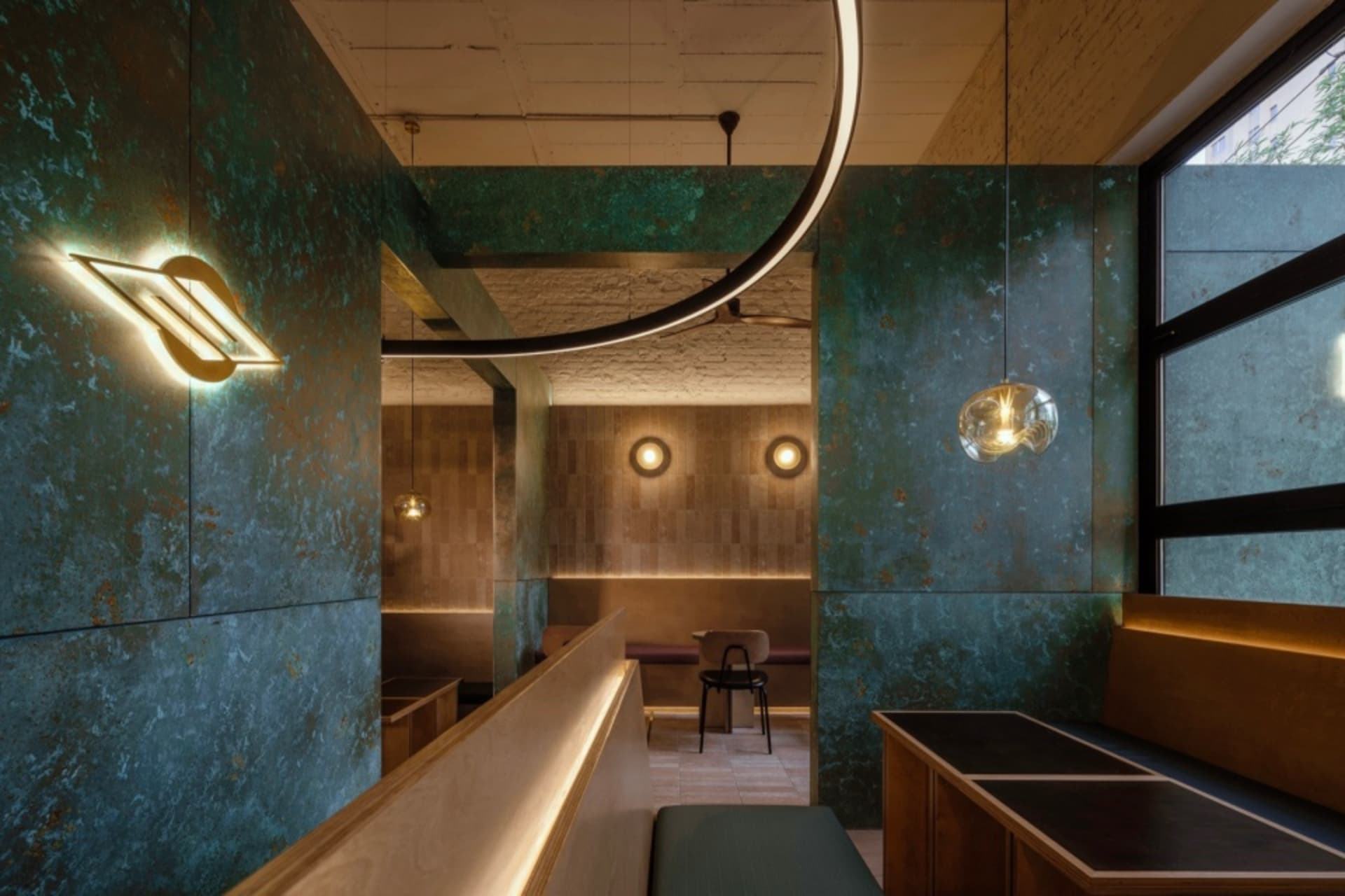 Modern industrial restaurant interior with metallic textured walls and contemporary lighting fixtures.