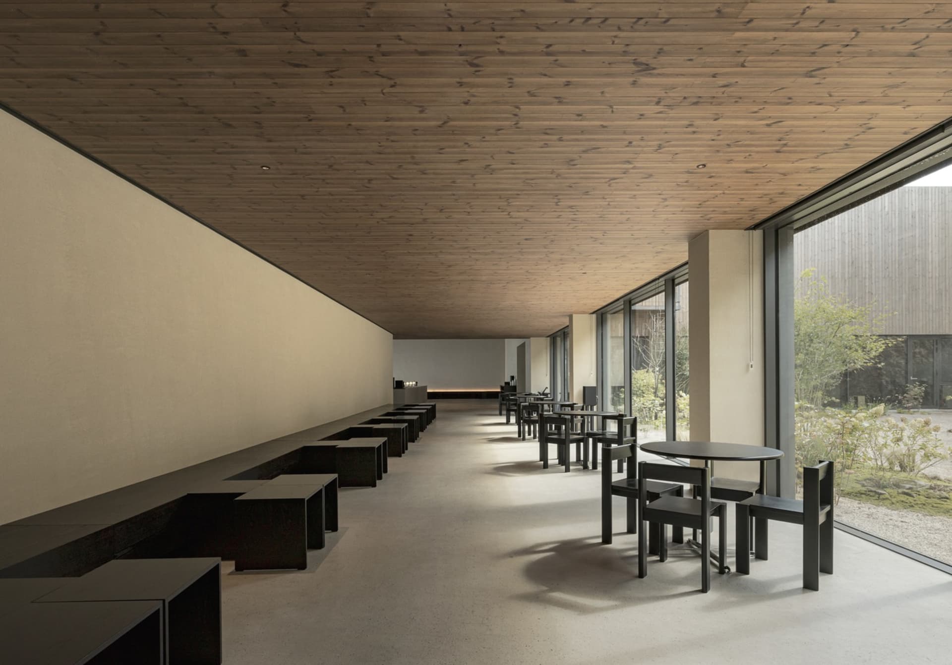 A minimalist industrial restaurant bar with concrete flooring and wooden accents.