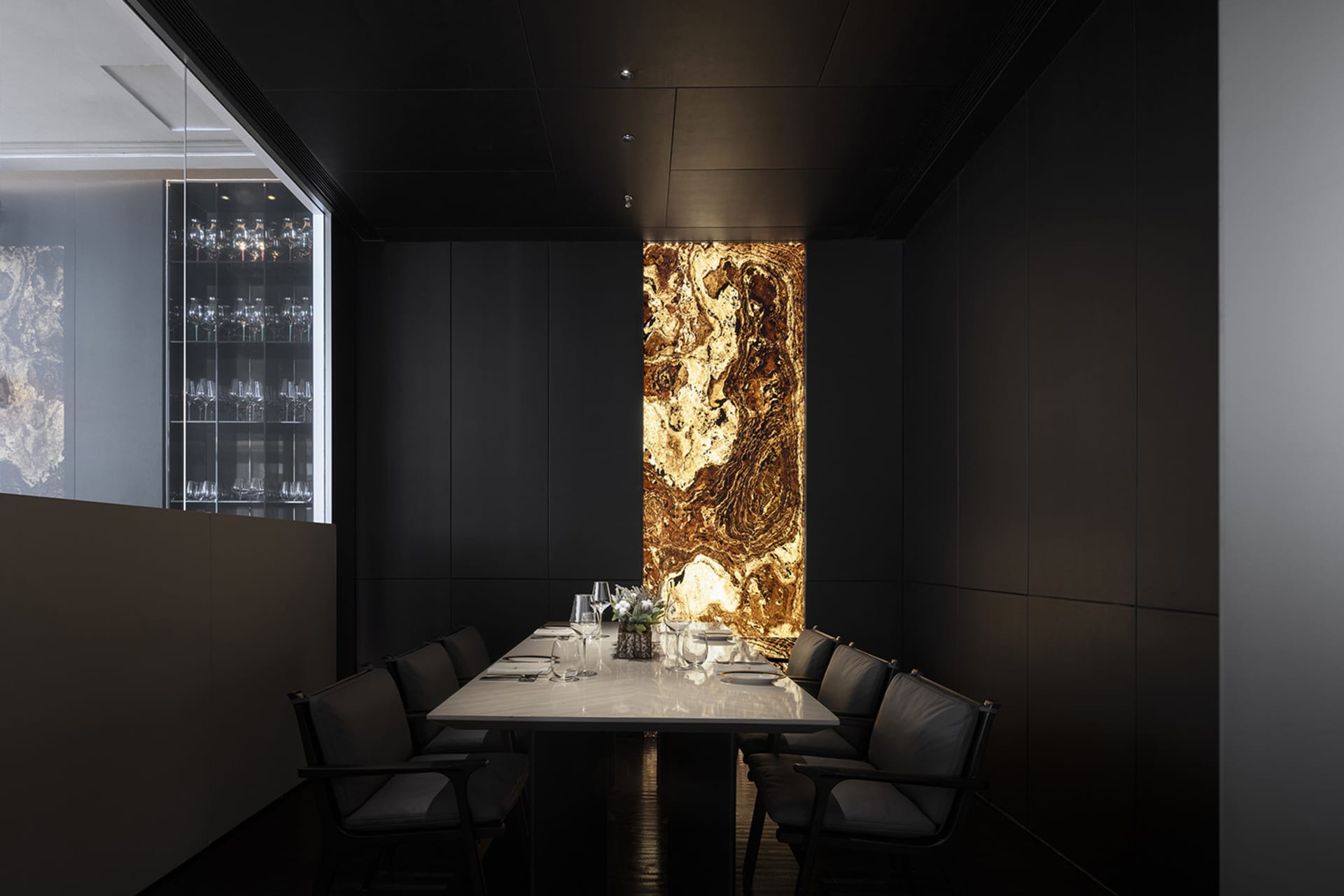 A modern private dining room with a sleek, minimalist design featuring a long table made of polished marble, surrounded by co