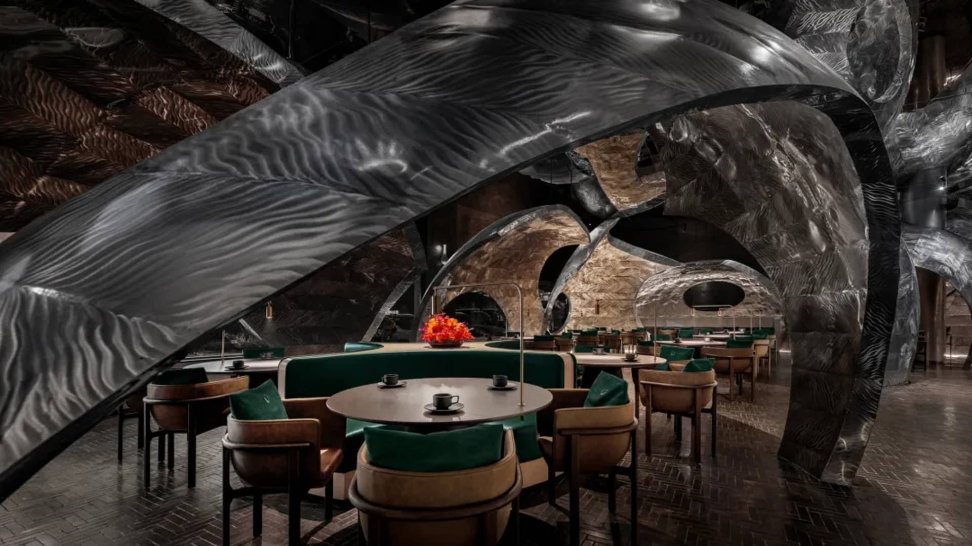 A modern restaurant interior featuring metallic, leather, and wooden materials.