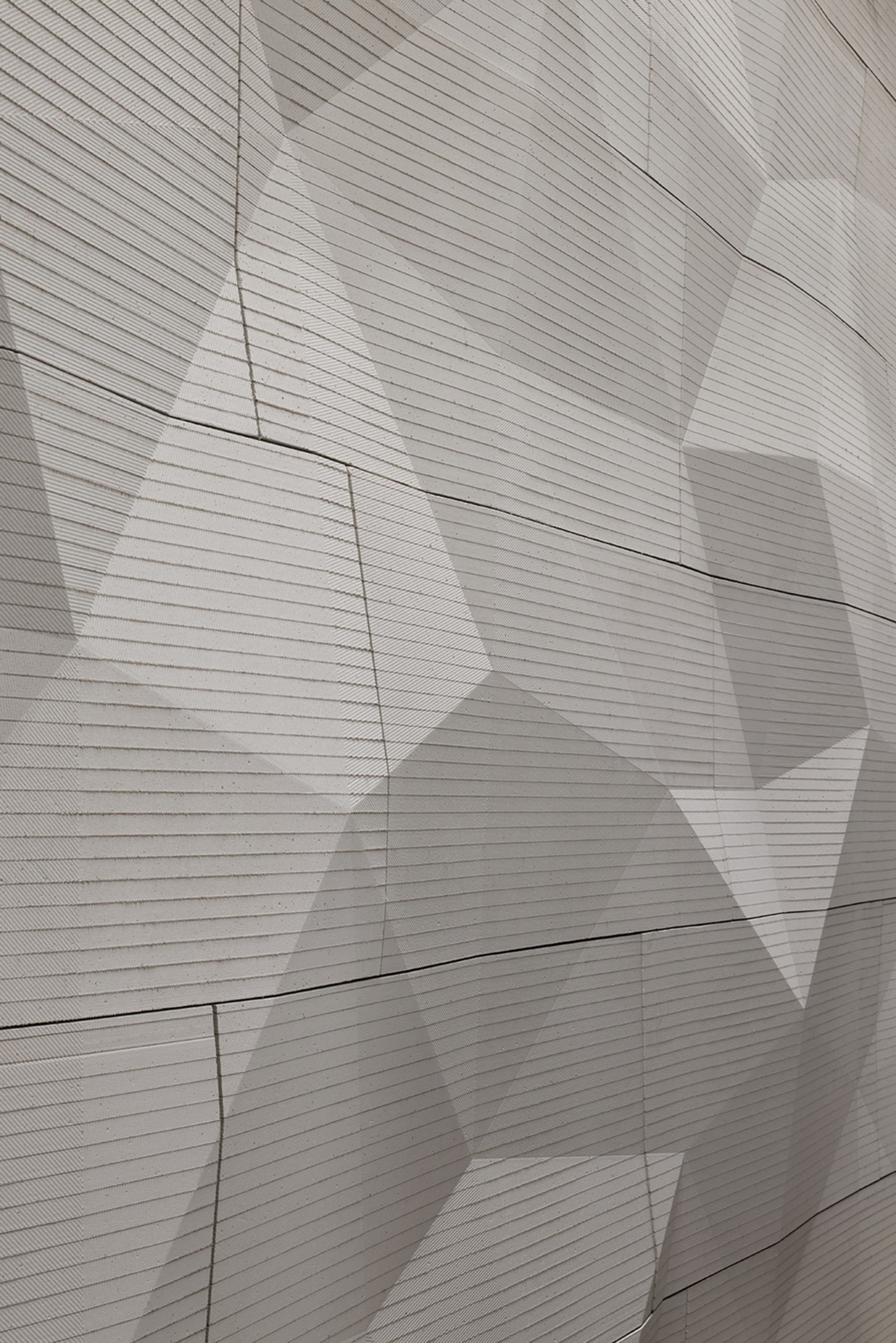 Modern architectural facade featuring a textured concrete surface with geometric patterns.