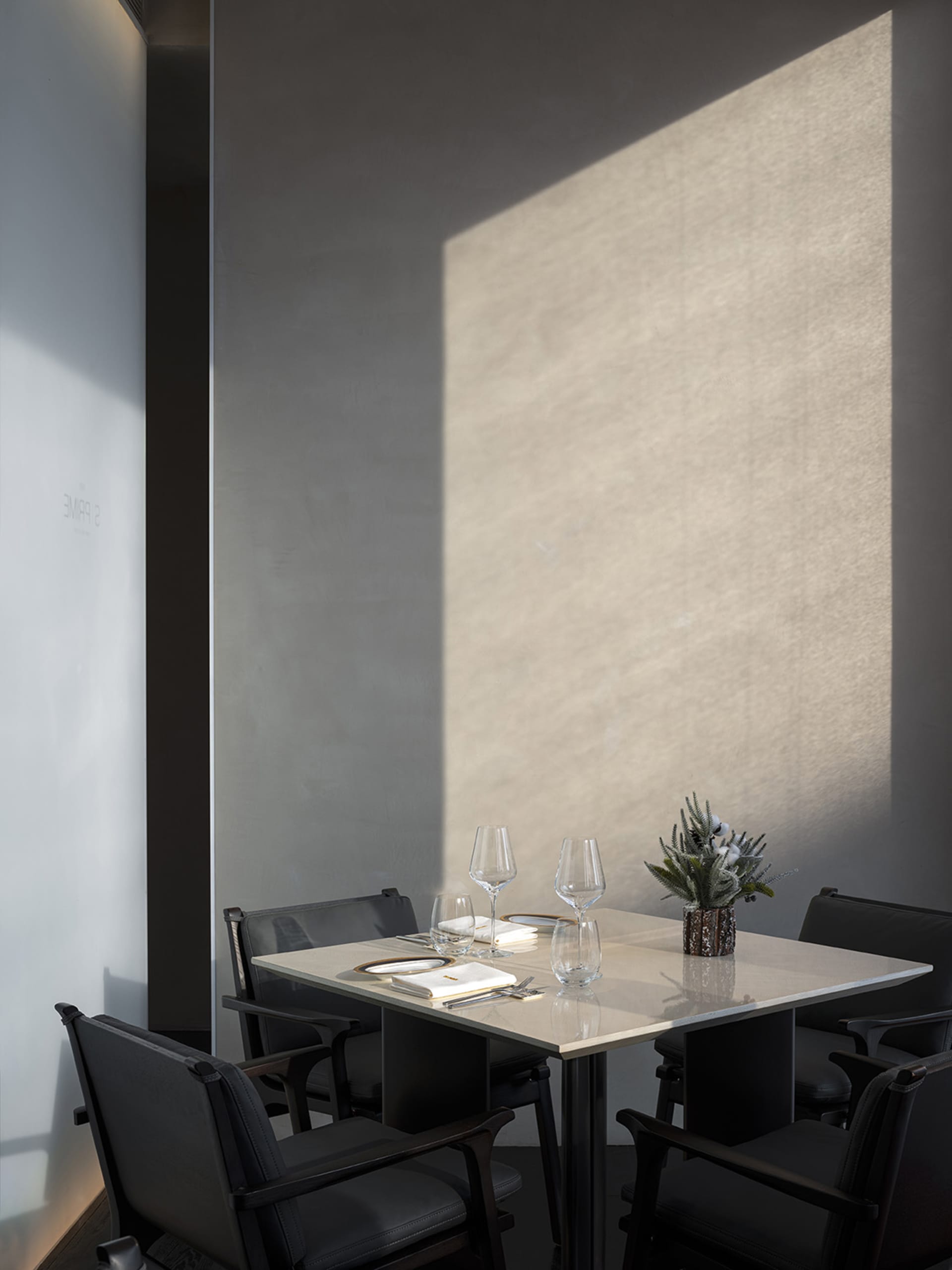 A minimalist restaurant interior with concrete and steel materials and elegant table setting.