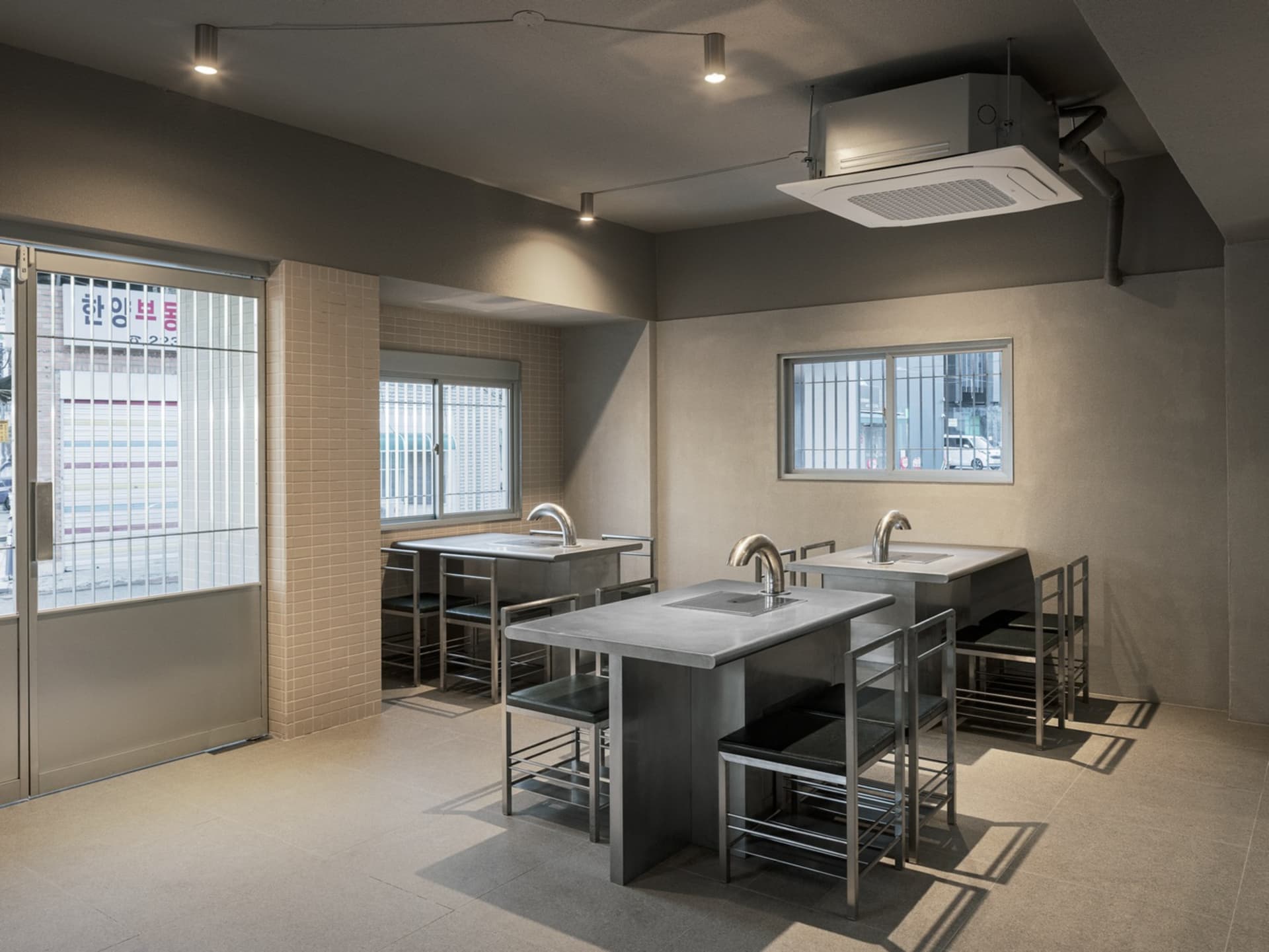 Industrial-style commercial kitchen with metal counters and stools.