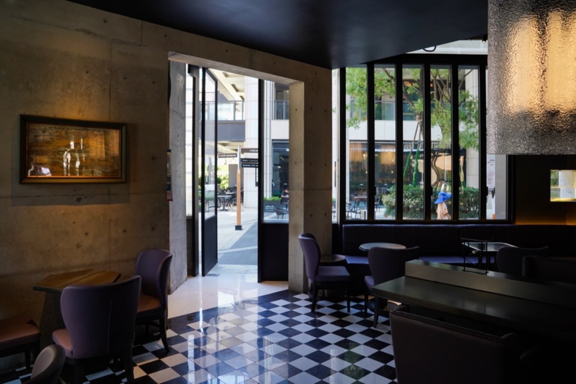 Modern interior of a restaurant with concrete walls, glass walls, and leather furniture.