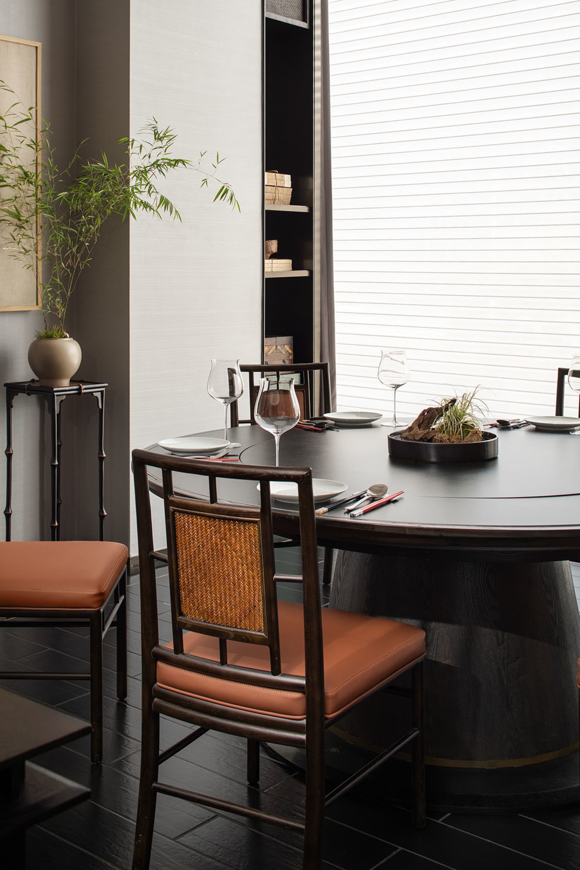 Modern dining room featuring a black wooden dining table, leather chairs, and minimalist decor.