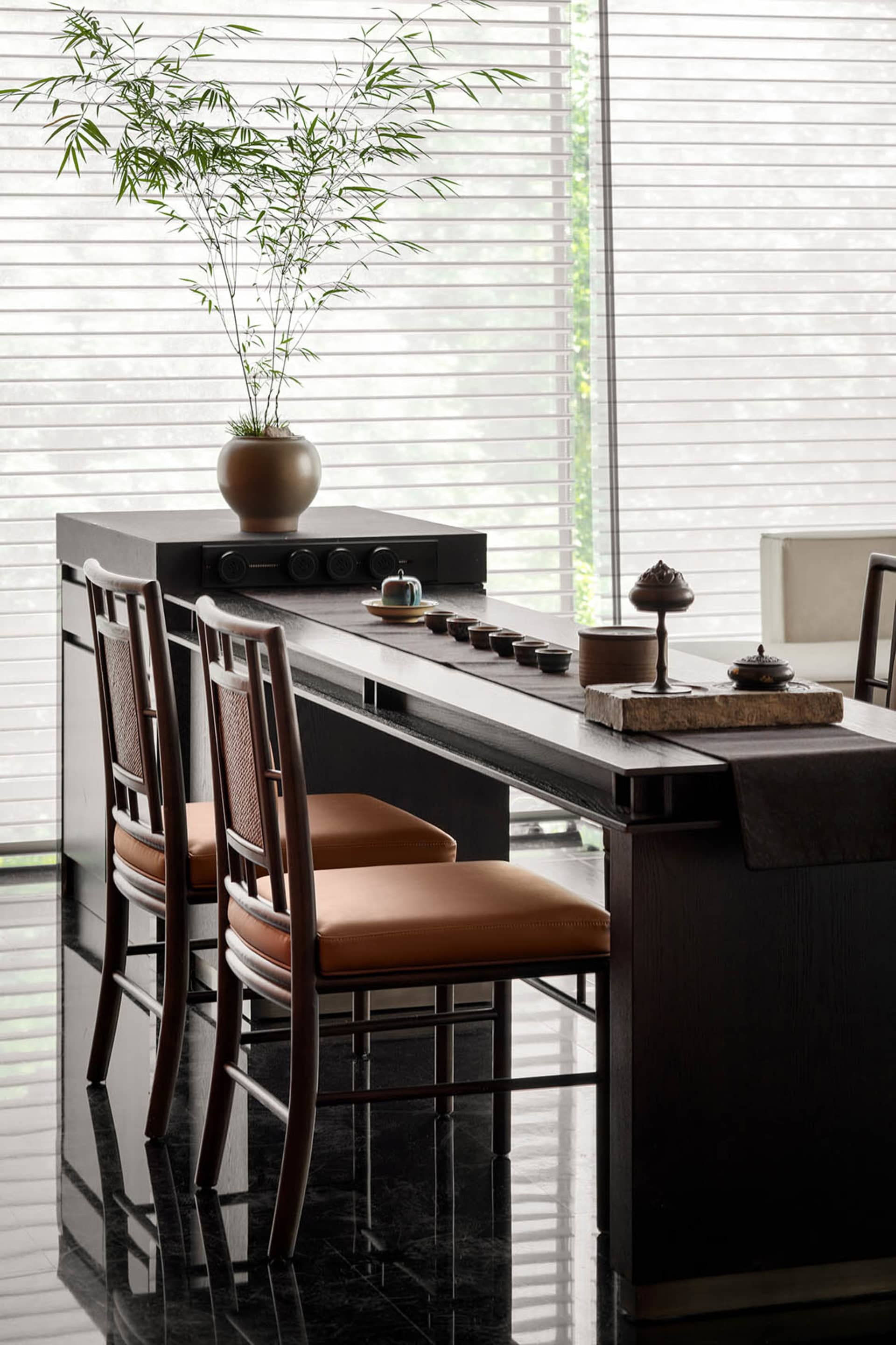 A modern interior scene featuring a sleek, dark wooden desk with a minimalist design, sitting chairs with brown cushions, and