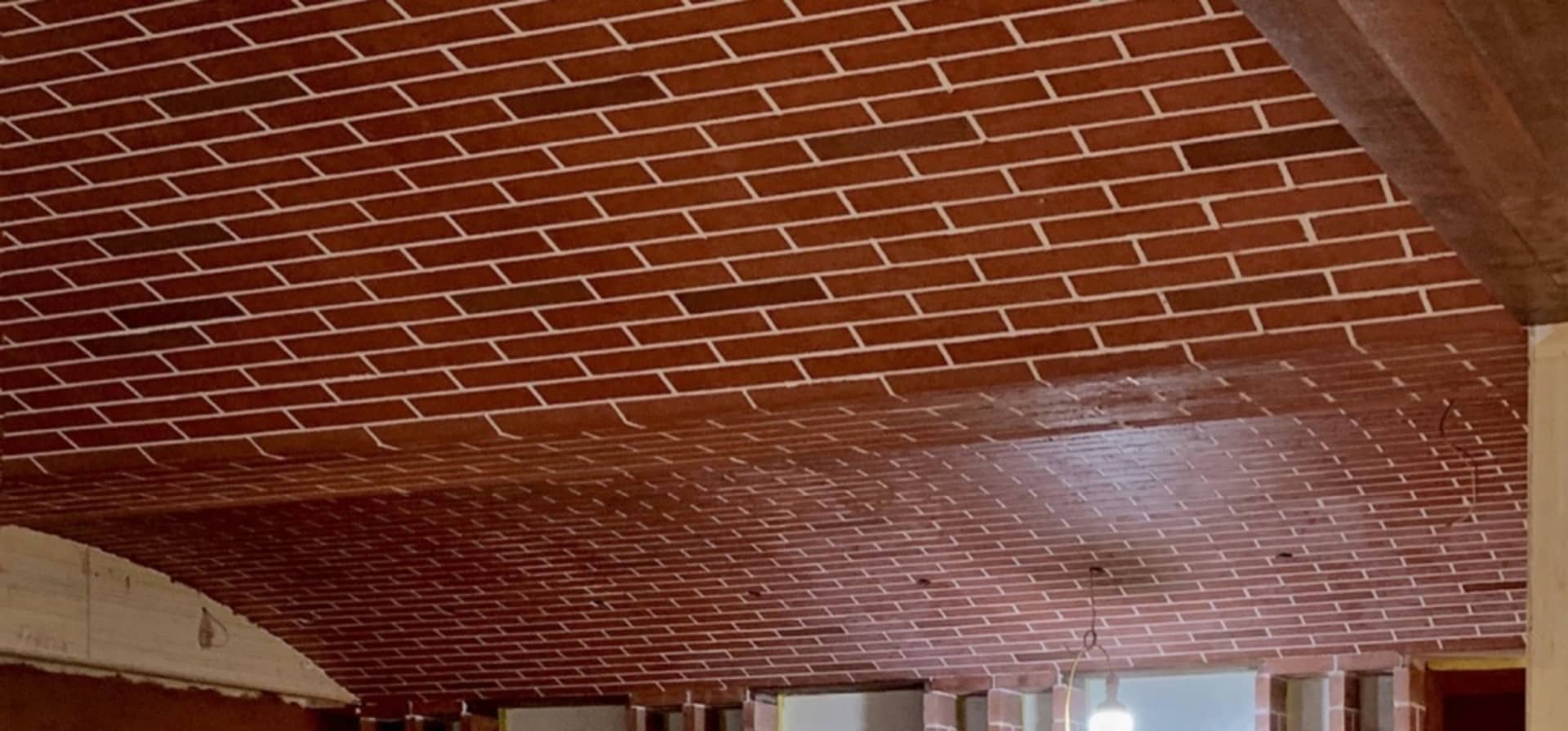 Industrial interior design featuring a brick ceiling with a central lamp.