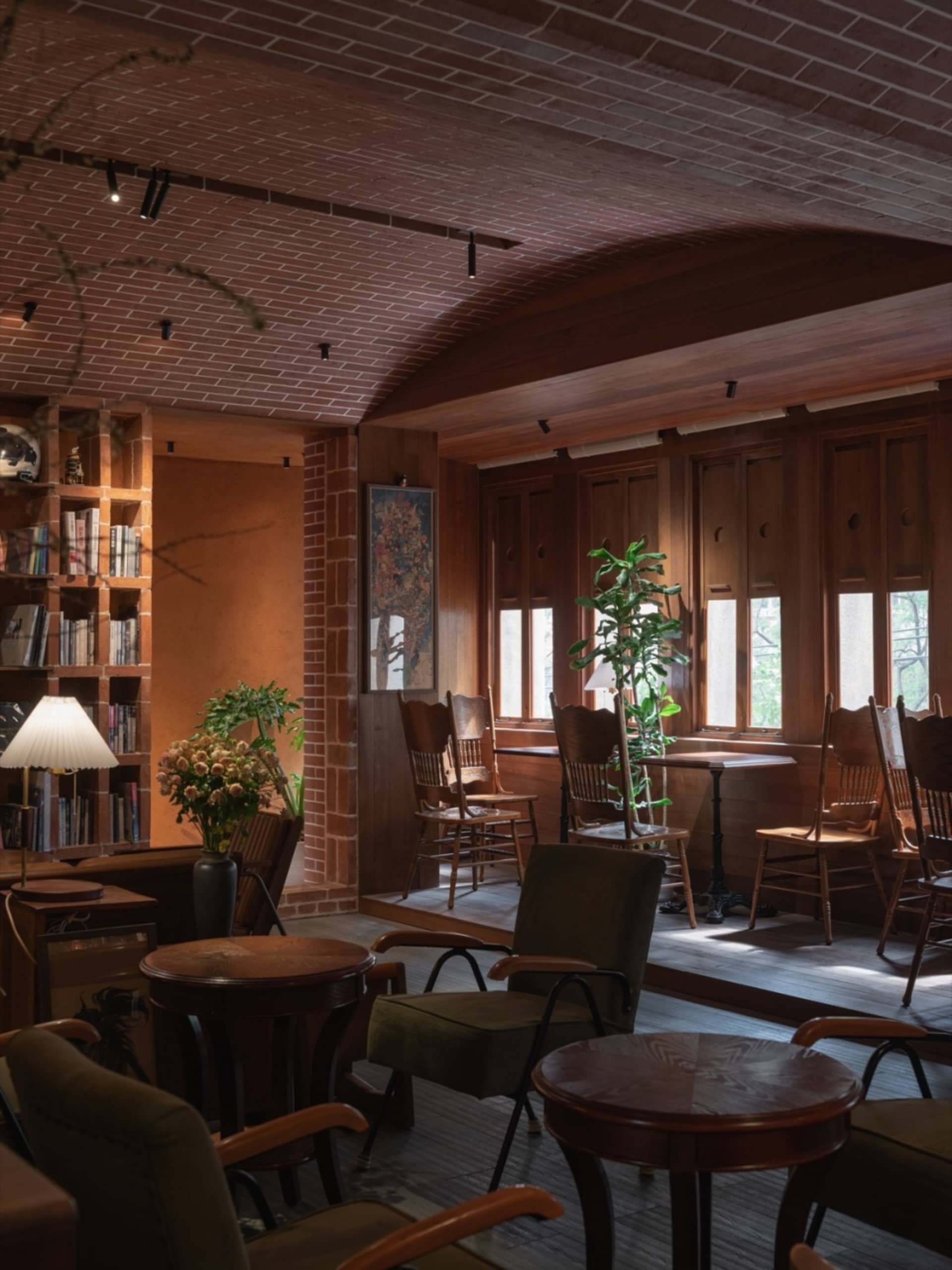 A cozy cafe interior with wooden furniture, brick ceiling, and natural light streaming through windows.