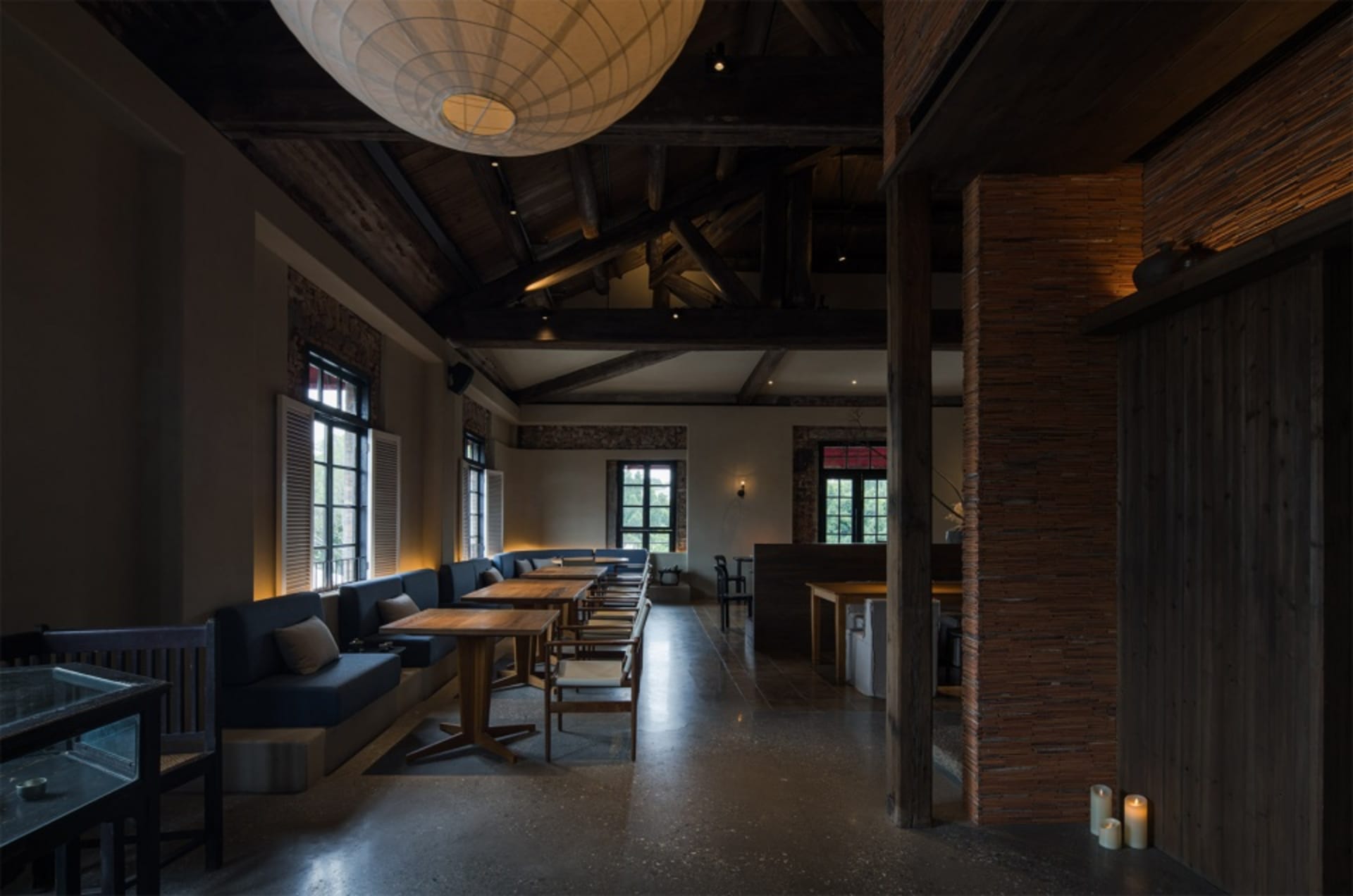 Industrial-style cafe interior with concrete flooring, brick walls, and wooden beams.