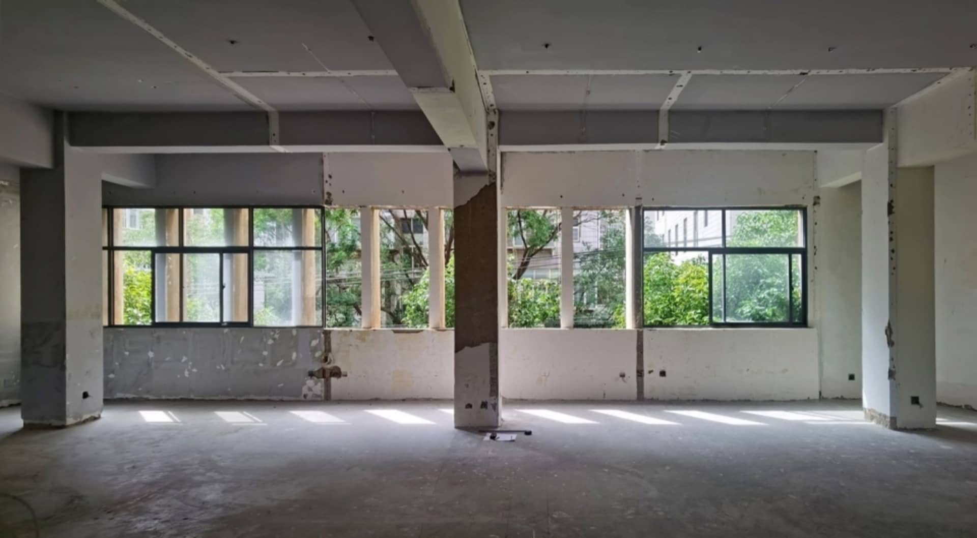 A spacious, modern office space with concrete walls and large windows.