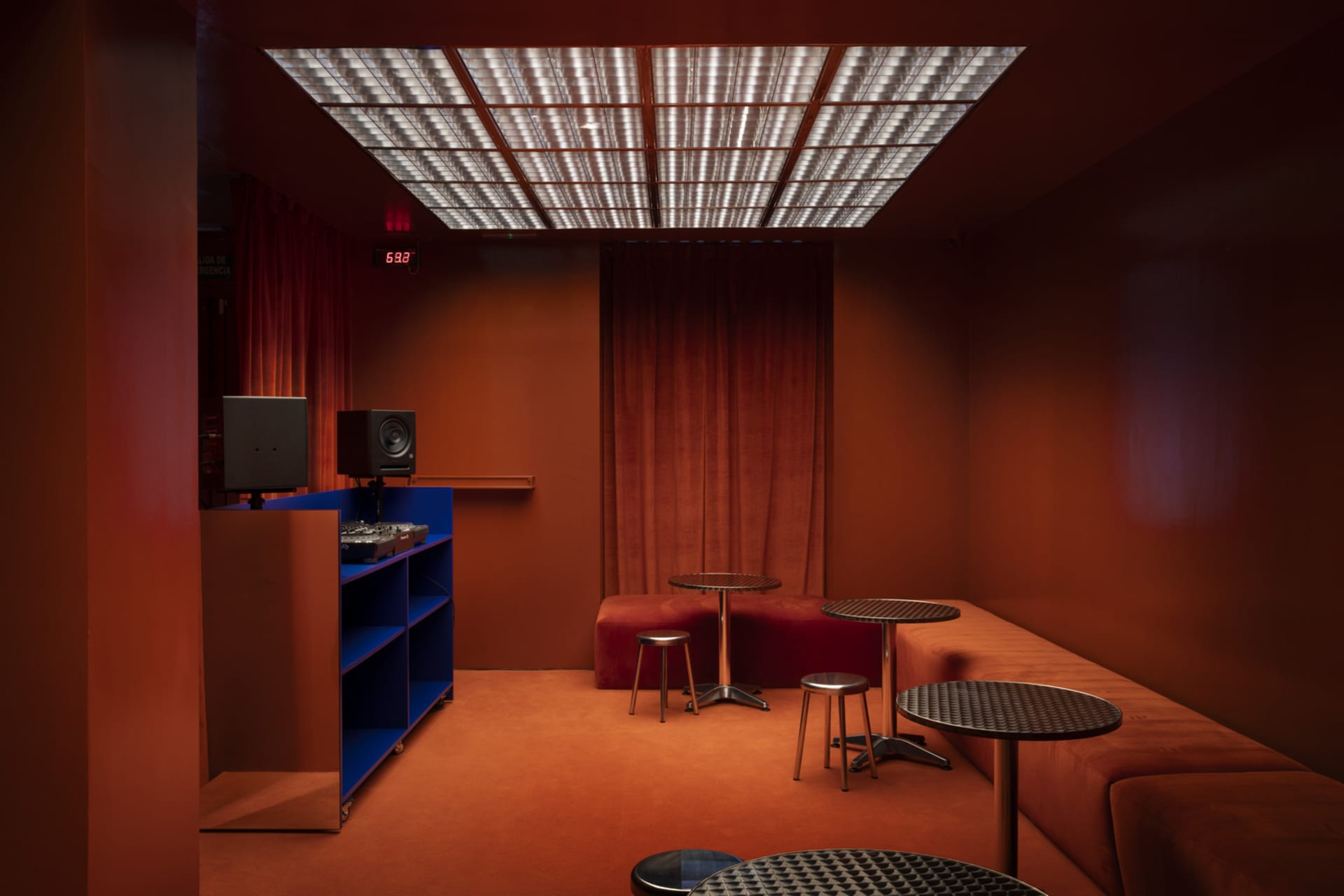 An industrial-style club room with metal tables, glass lighting, and fabric seating.