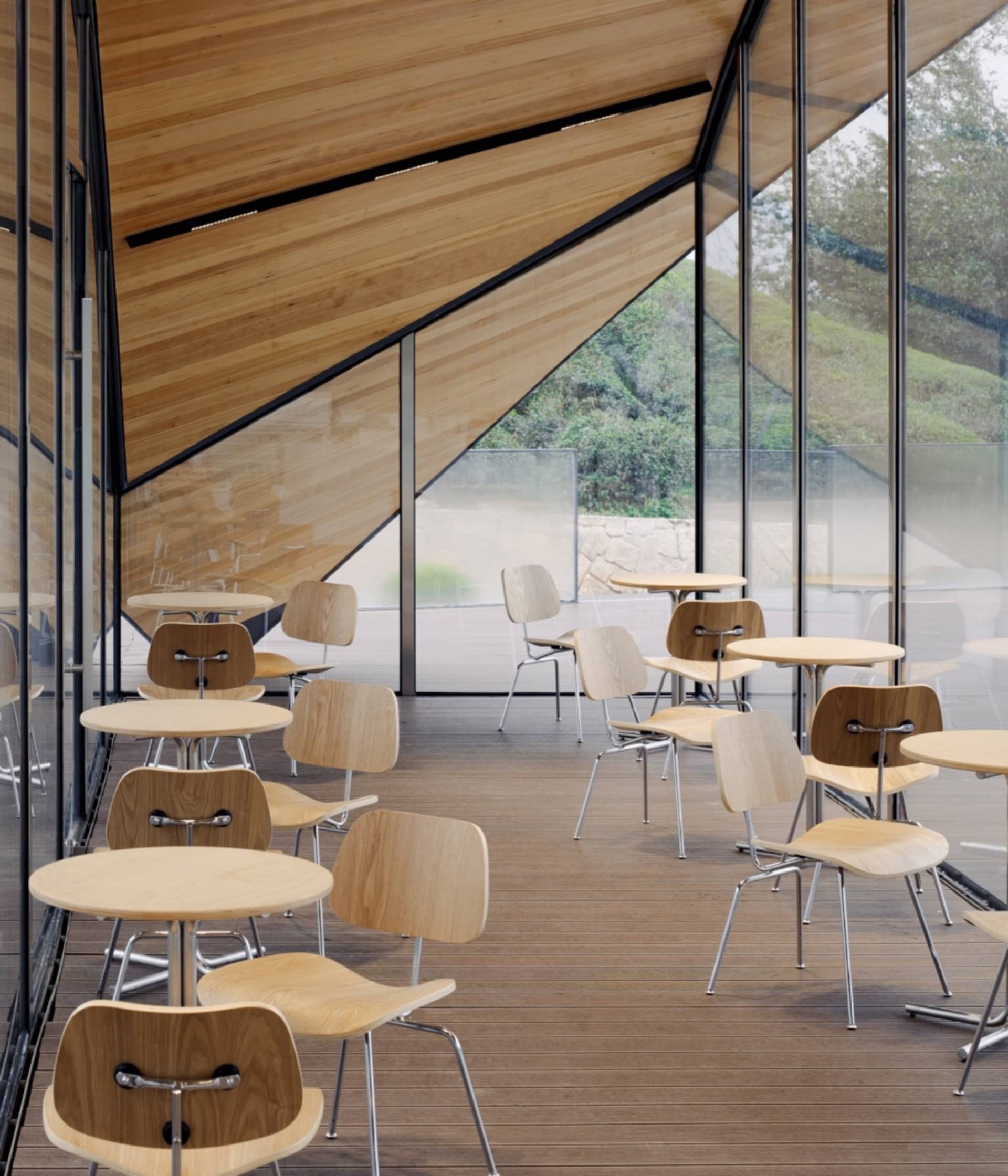 Modern cafe interior with wooden tables and chairs, large glass windows, and a wooden slanted ceiling.