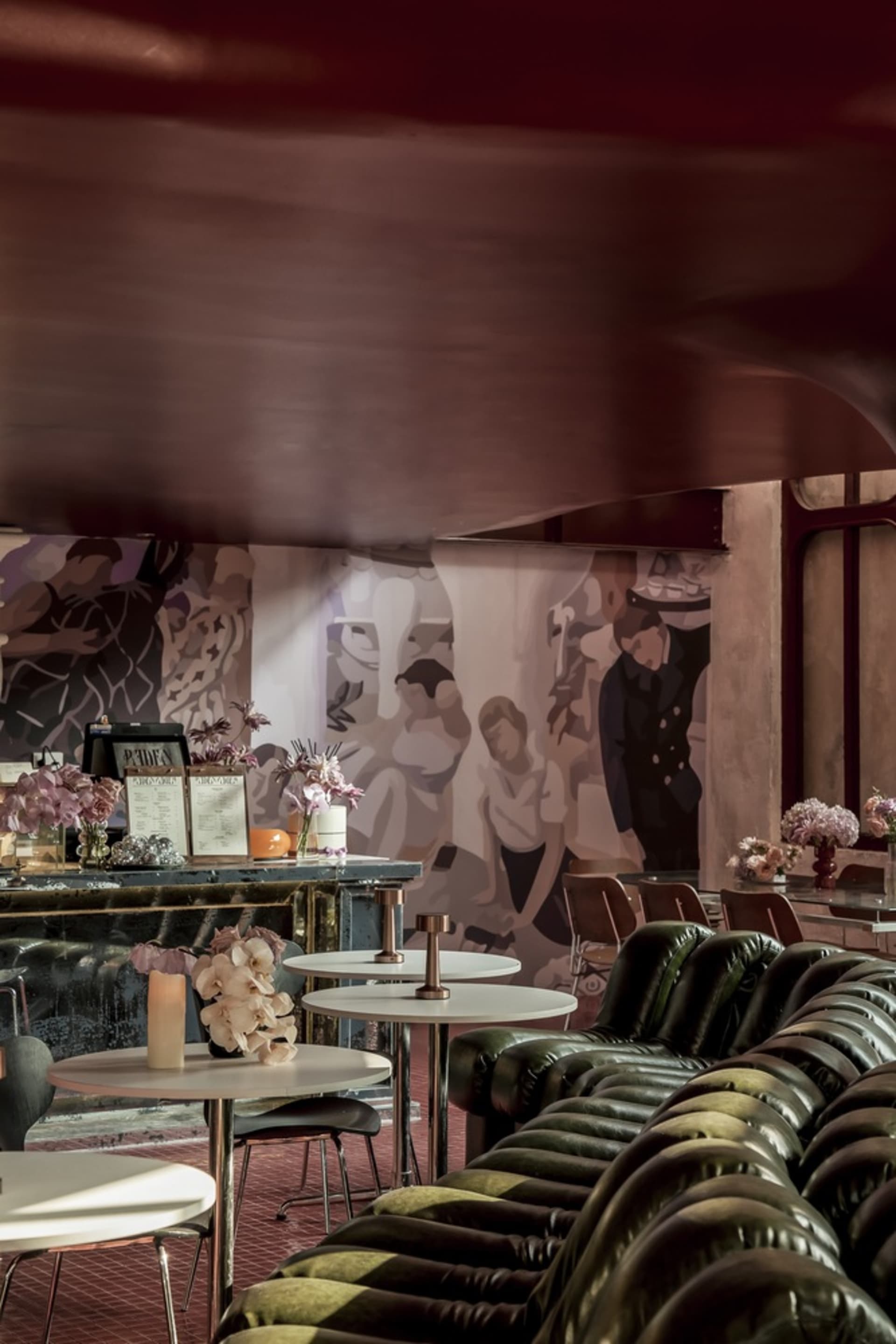 A modern restaurant interior with white tables, flower arrangements, and a leather sofa.