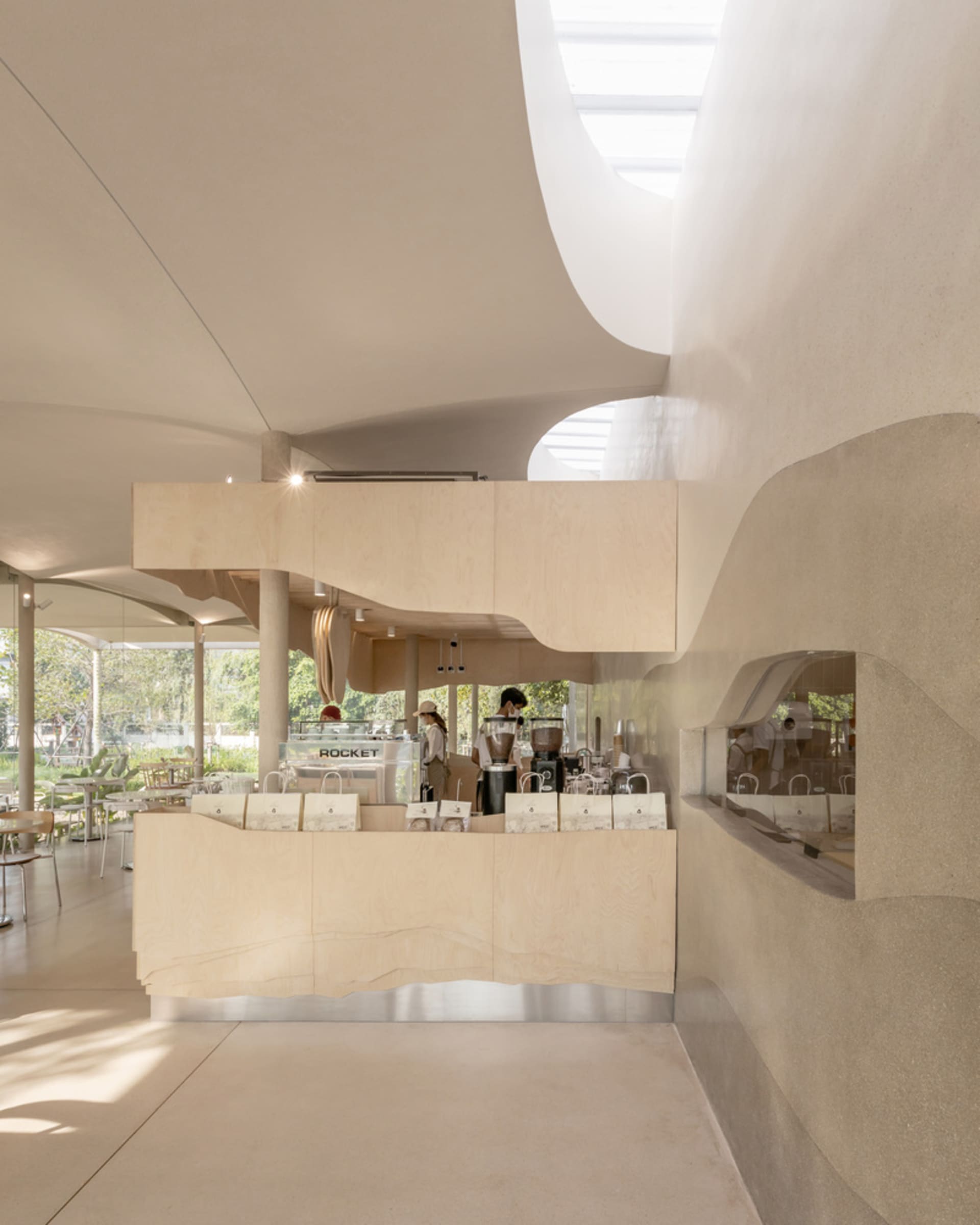 Interior view of a modern coffee shop featuring a light wood counter and glass walls