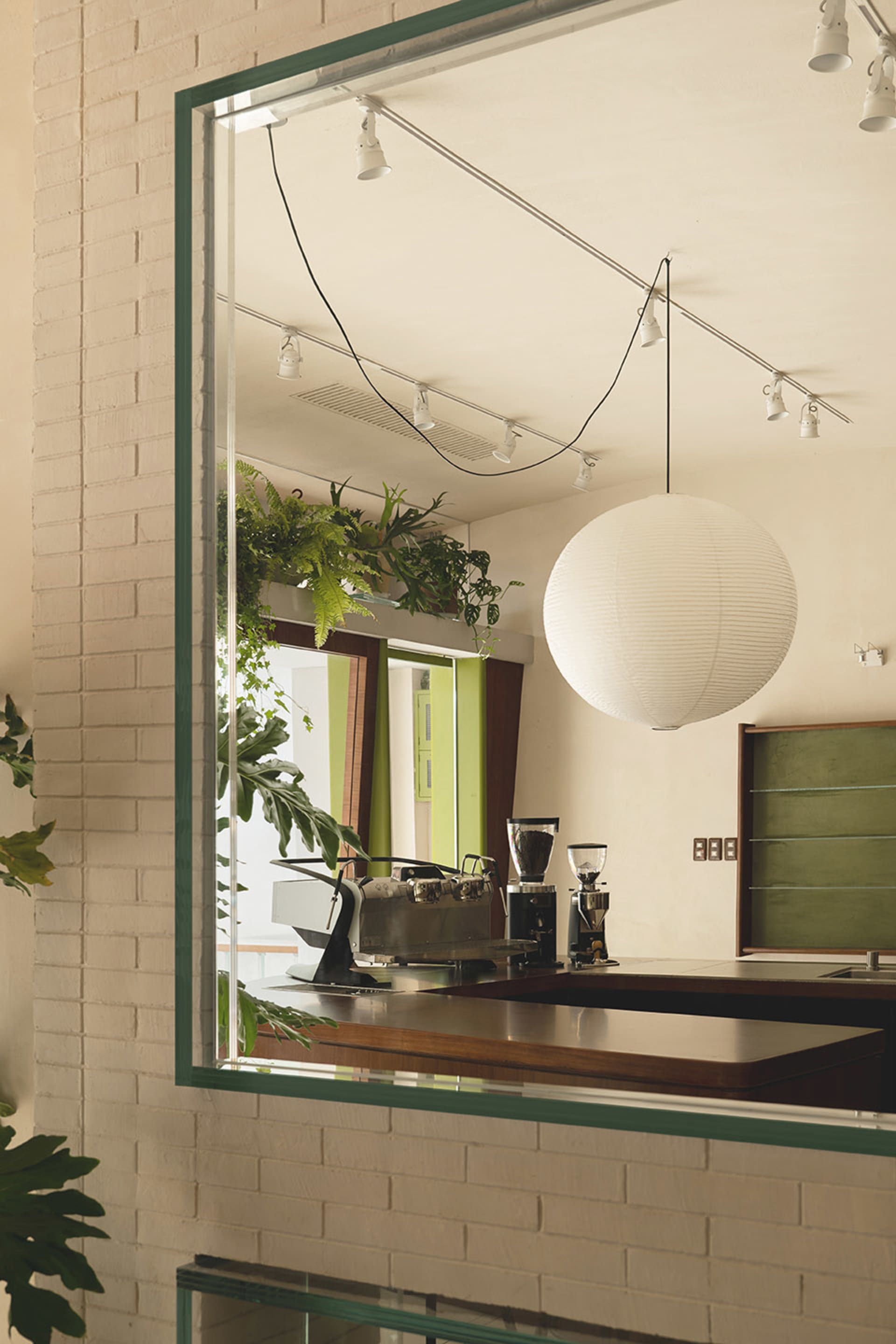 A modern coffee shop featuring brick walls, concrete counters, and greenery.