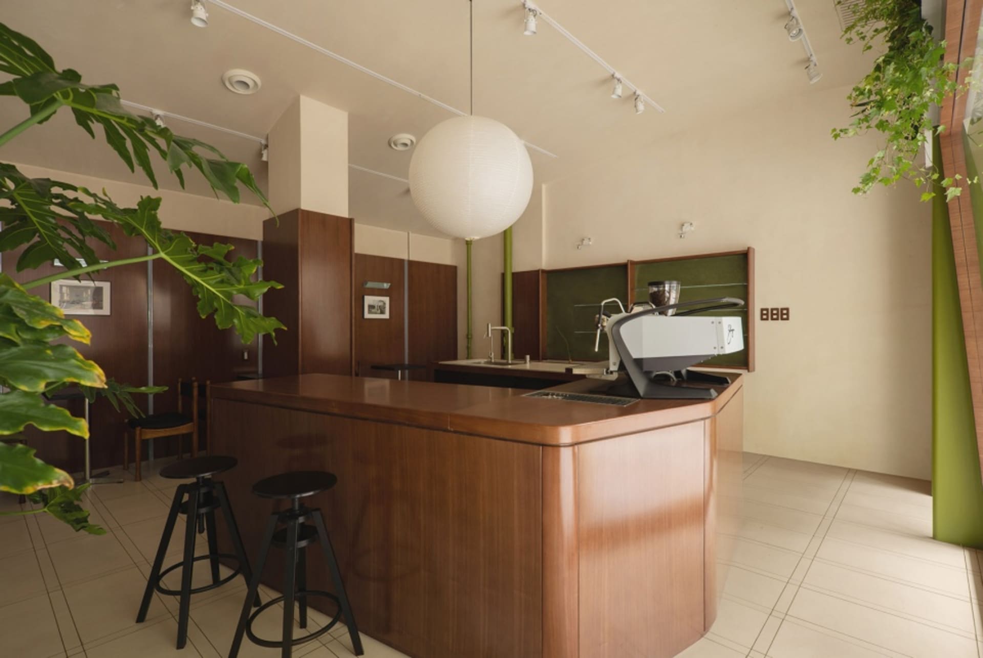 現代咖啡店廚房,配有木質吧台、綠植與大型球形燈具。