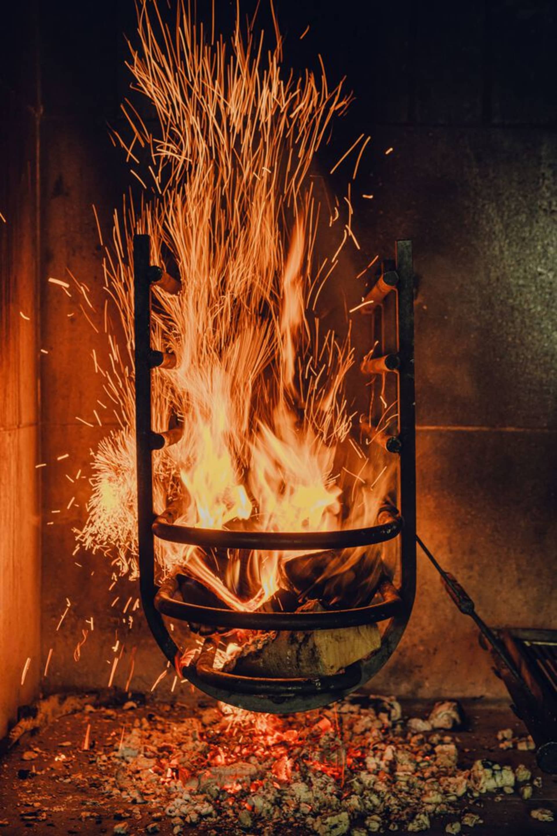 A metal fireplace with sparks flying from it.