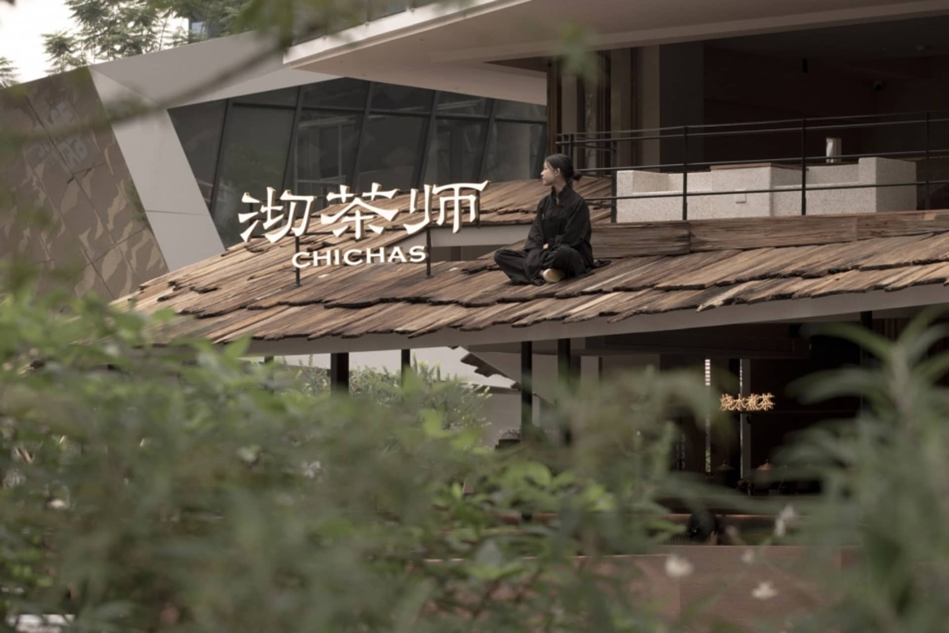 A person sitting on a wooden rooftop of a restaurant with a modern architectural design.