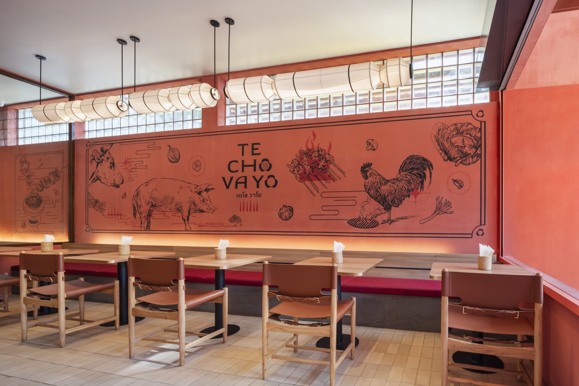 現代餐廳室內，鮮豔紅色牆面彩繪各種食物圖案，並寫有「TE CHÓ VAYÓ」字樣。