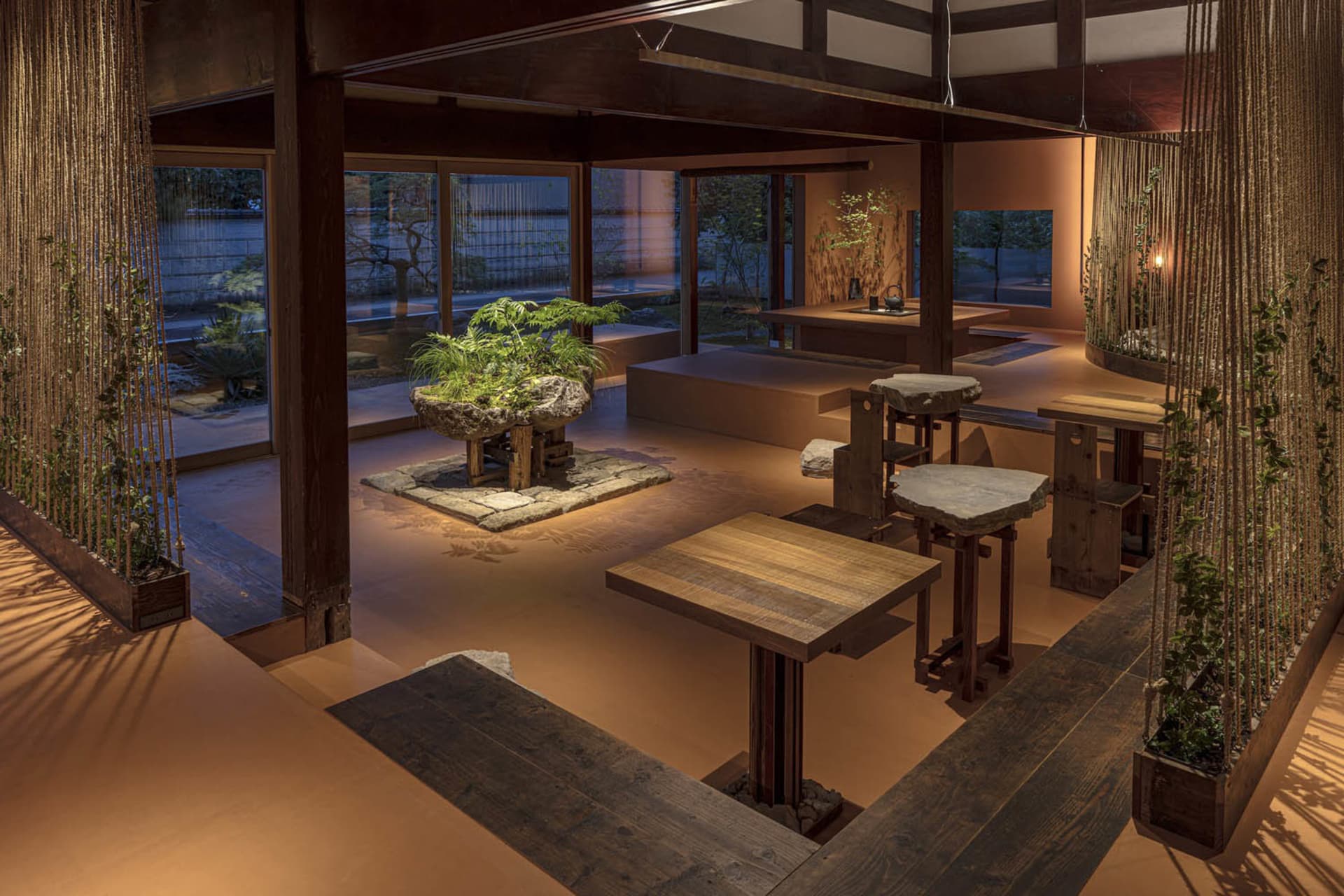 A modern living space featuring wooden furniture and a central stone plant display.