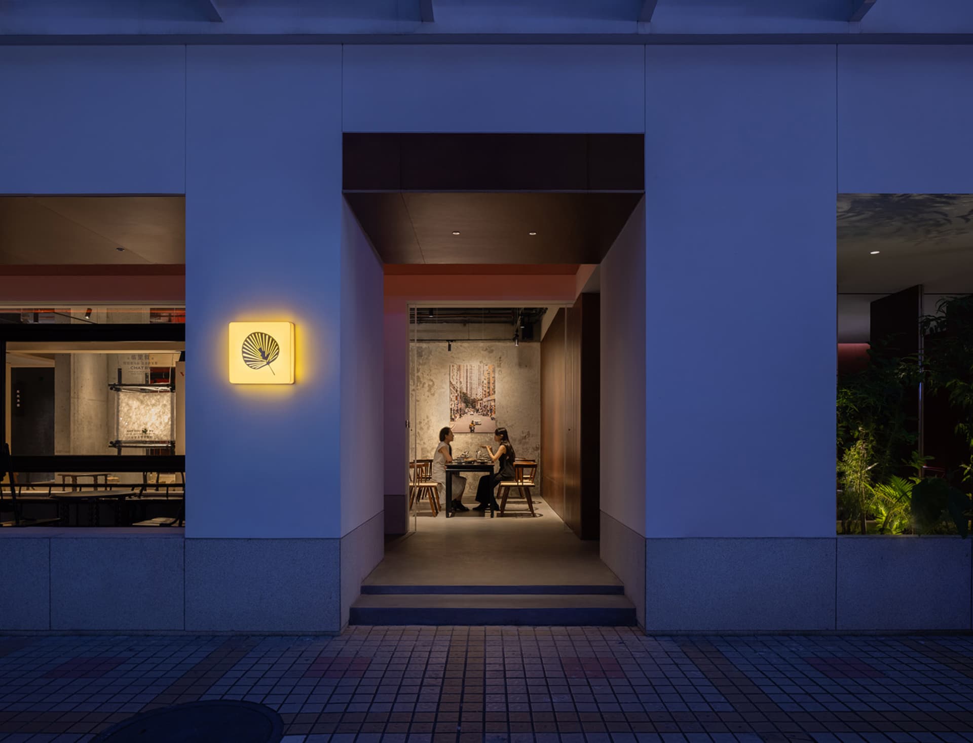 人們坐在現代餐廳的餐桌旁，室內有混凝土牆面與地板。