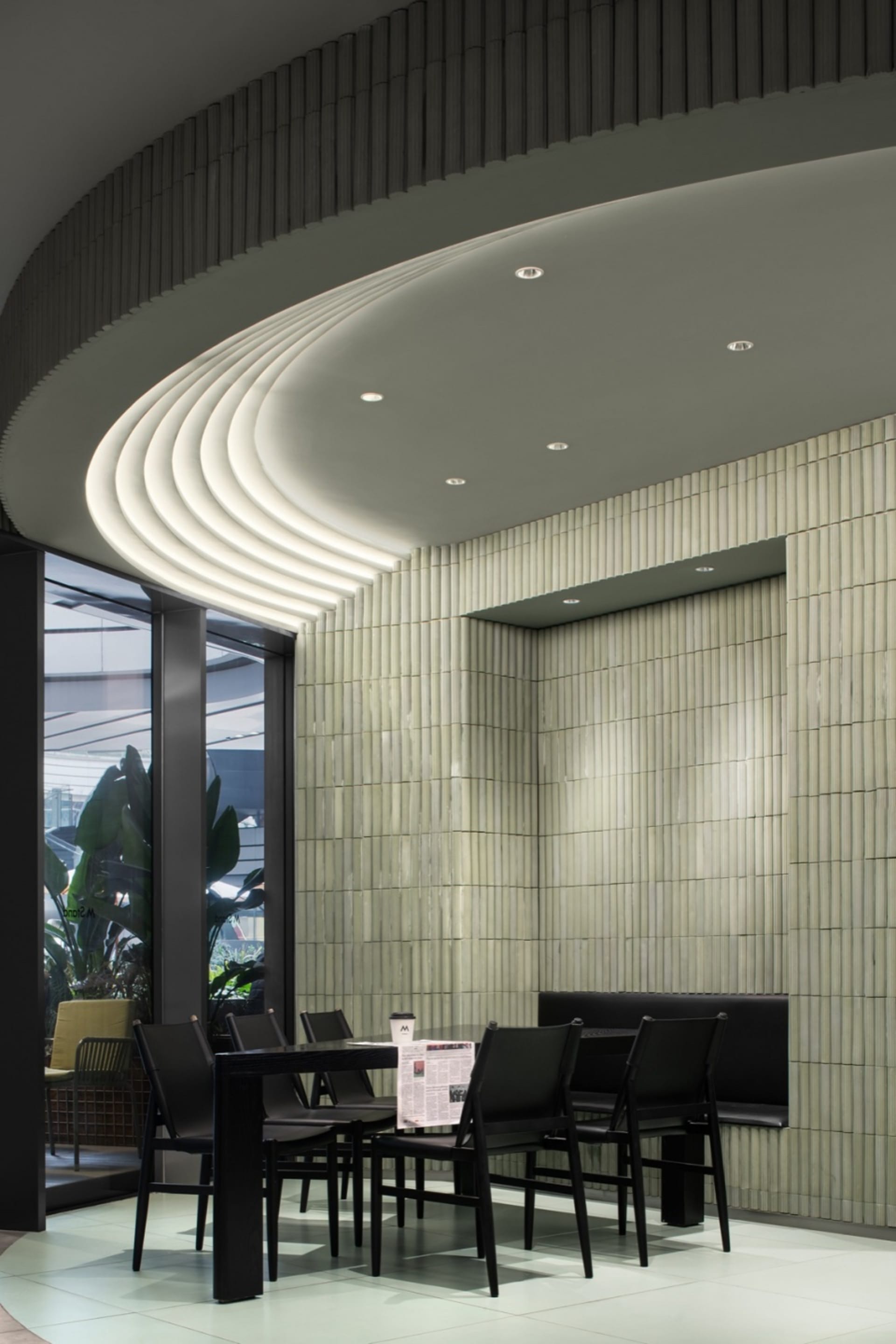 Modern restaurant interior with white tile walls and black furniture, featuring a cozy seating area and elegant design.