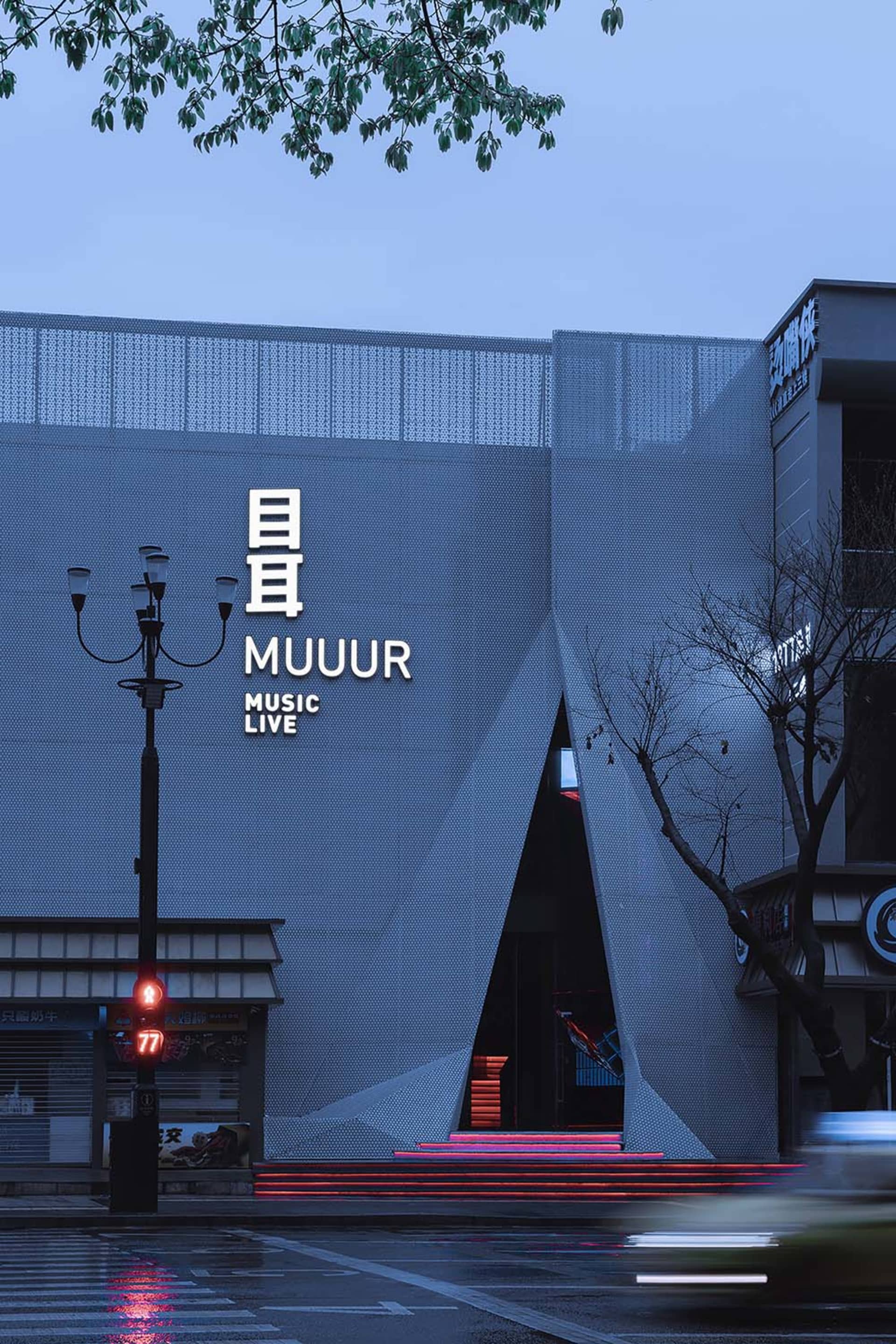 Modern, metallic-clad music live venue at dusk with illuminated steps.