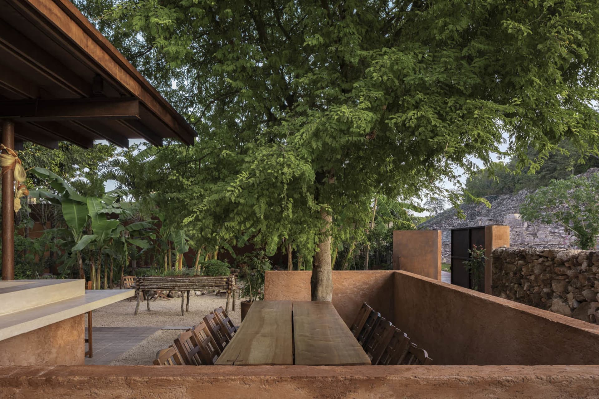 A corner of an urban green space with sandstone and concrete structures, surrounded by lush greenery and trees.
