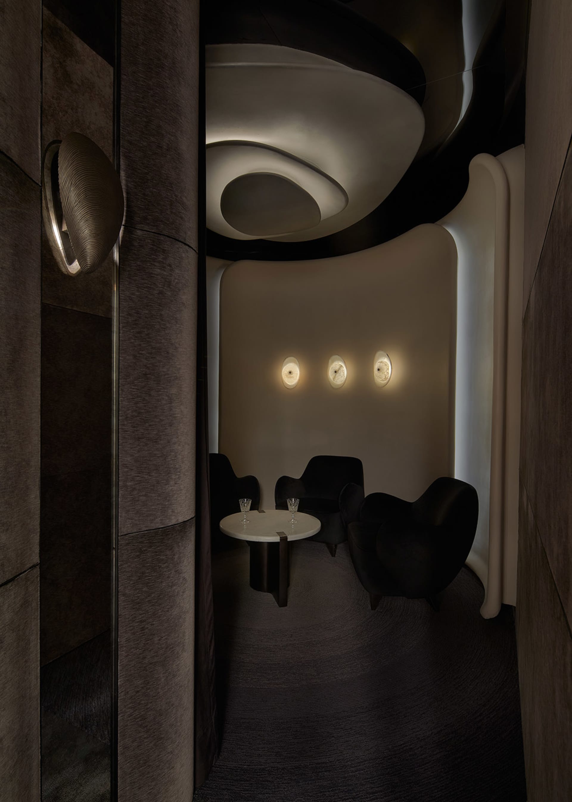 A modern bar with concrete walls and a circular table with two glasses of water.