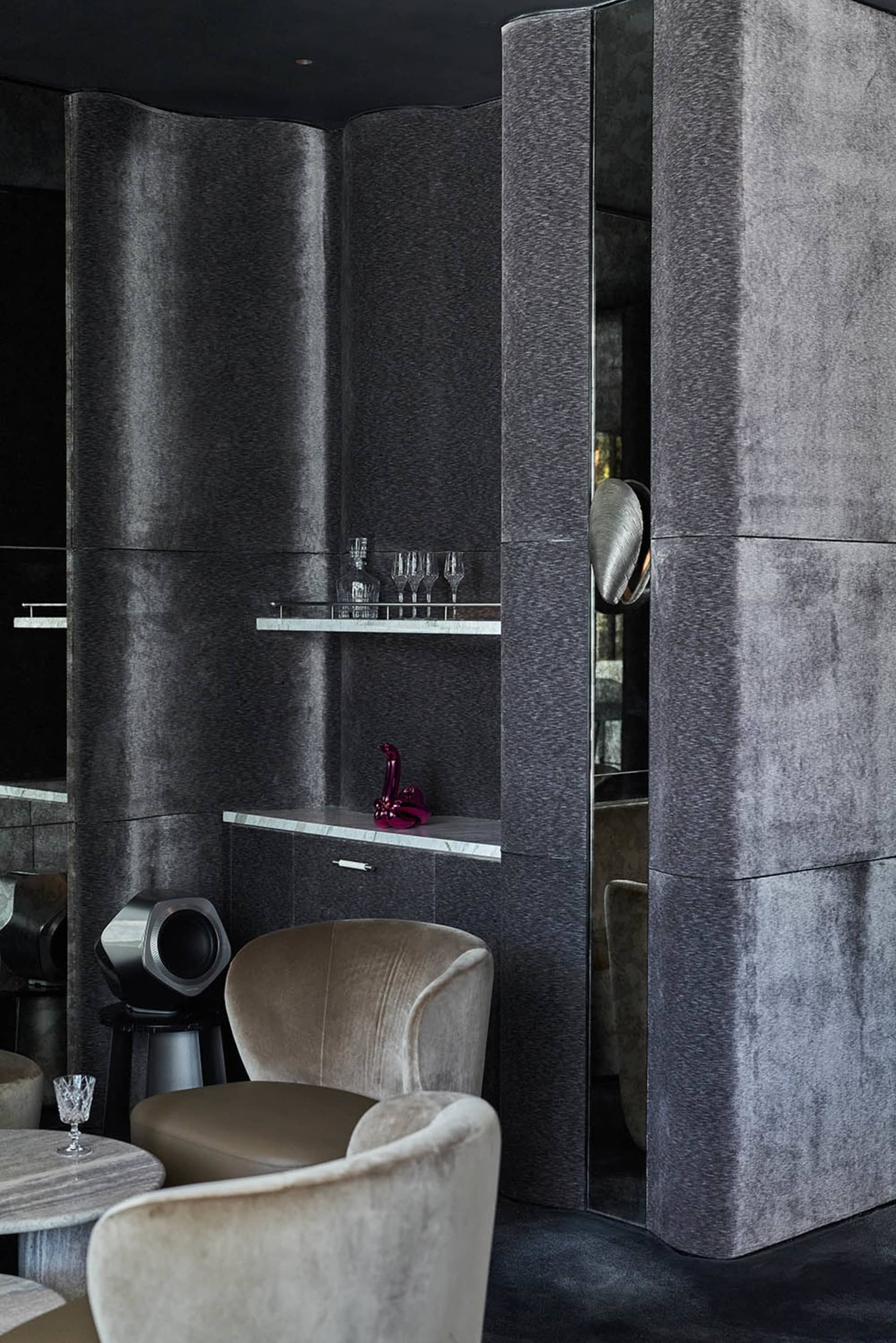 A modern bar interior featuring velvet-textured seating and marble accents.