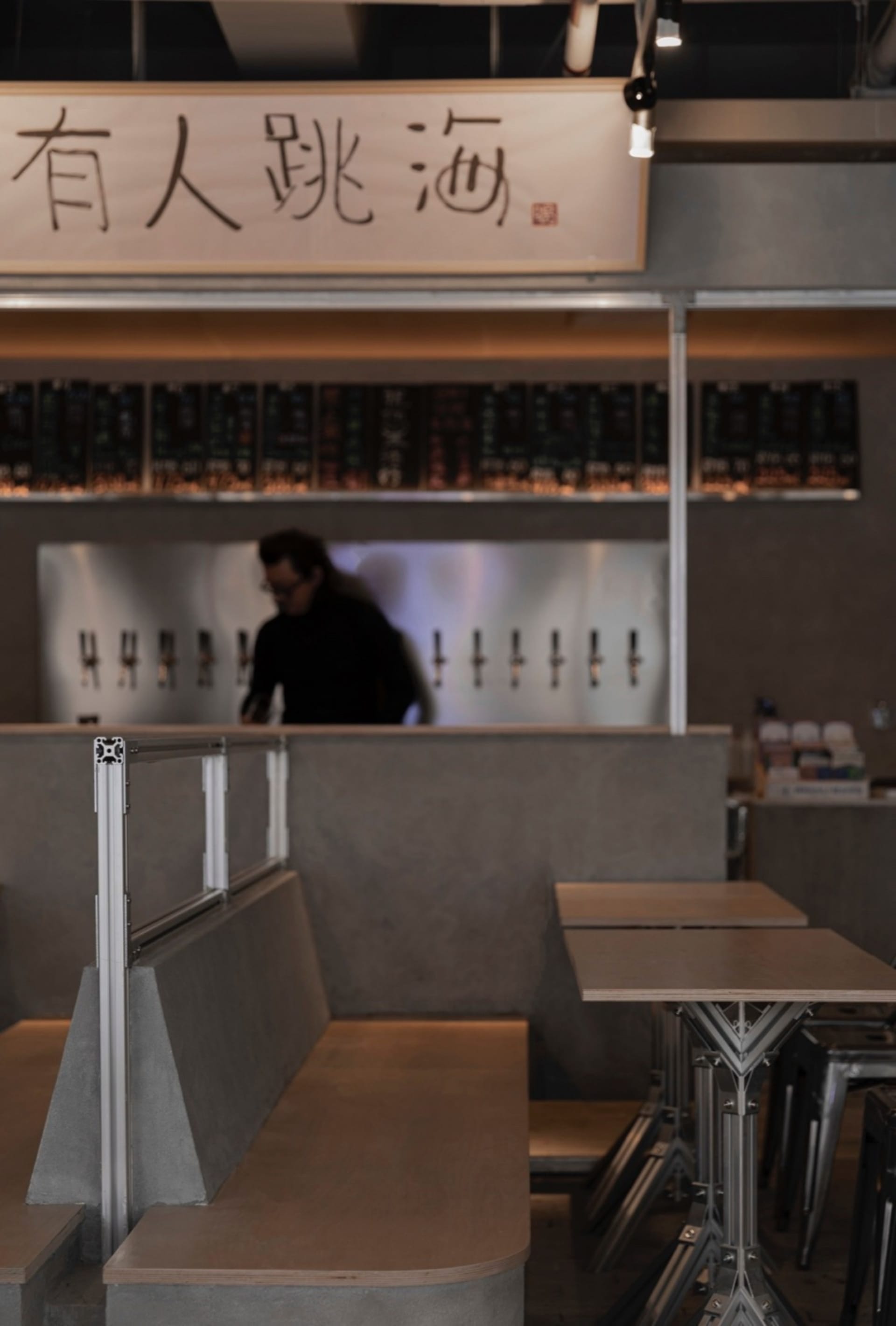 Concrete restaurant interior with industrial design elements, featuring a dark-colored table and a counter with a modern aest