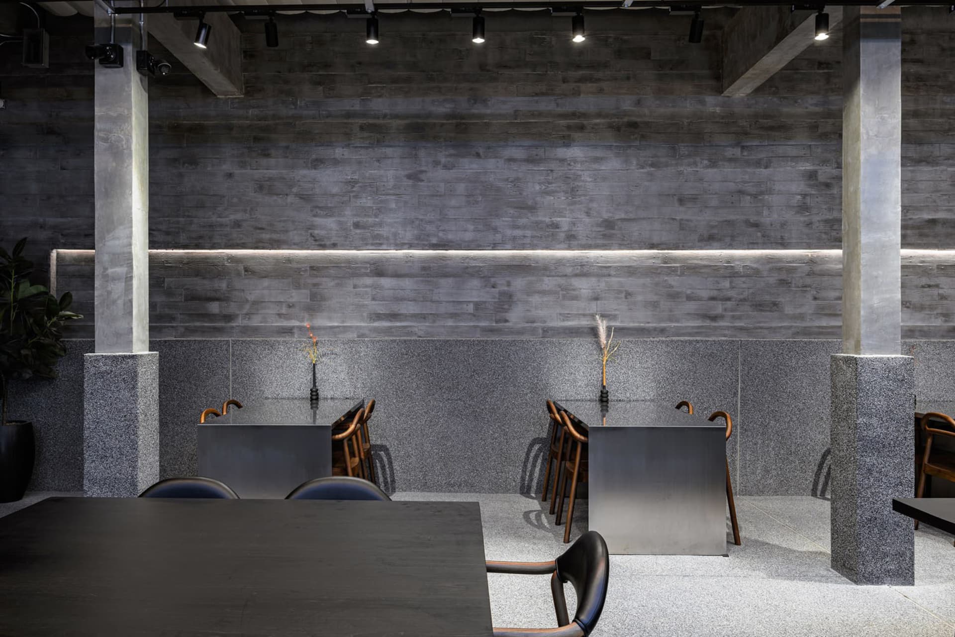 Modern restaurant interior with industrial design elements, featuring concrete, granite, and metal materials.