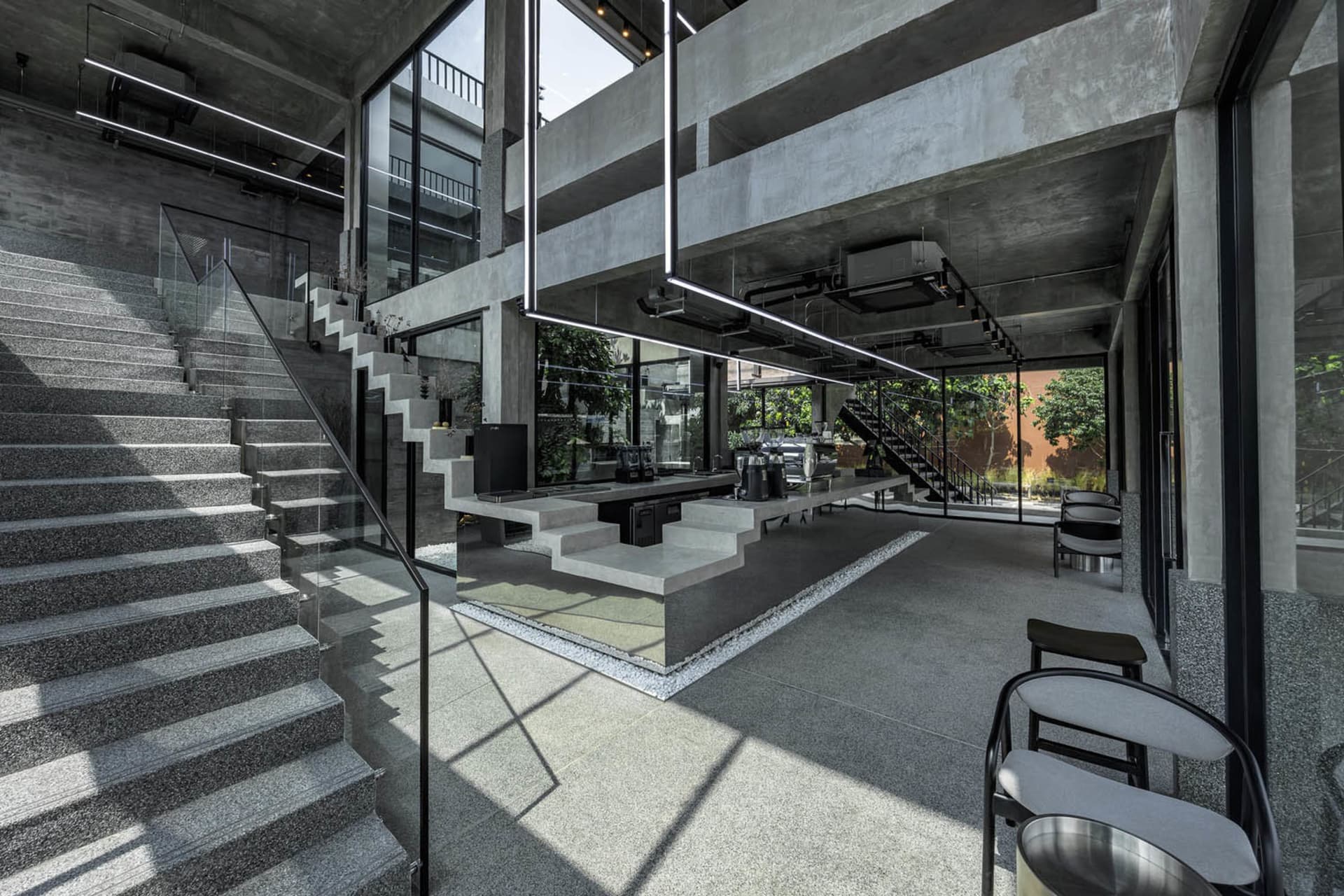 Modern industrial coffee shop with concrete, glass, and metal materials.