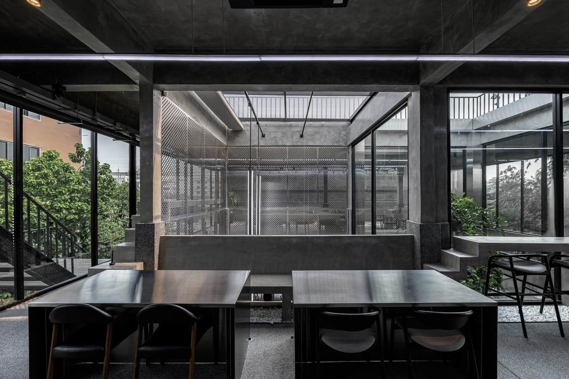 A minimalist office space with concrete walls, tables, and chairs.